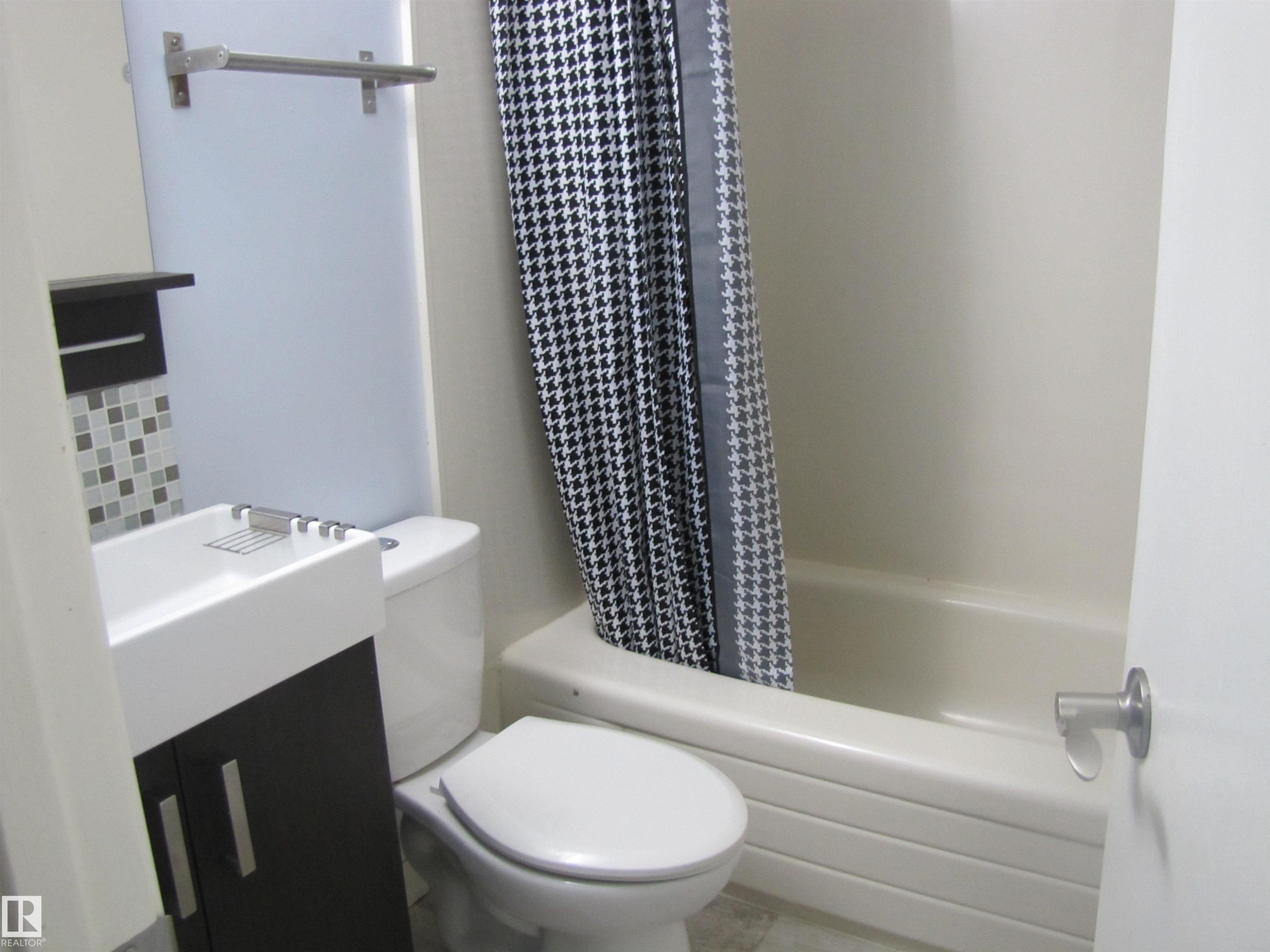Bathroom featuring a white vanity with a dark cabinet base, a toilet, and a shower/tub combination with a patterned shower curtain - 3617 43A Avenue, Edmonton, AB - Indoor Photo Showing Bathroom