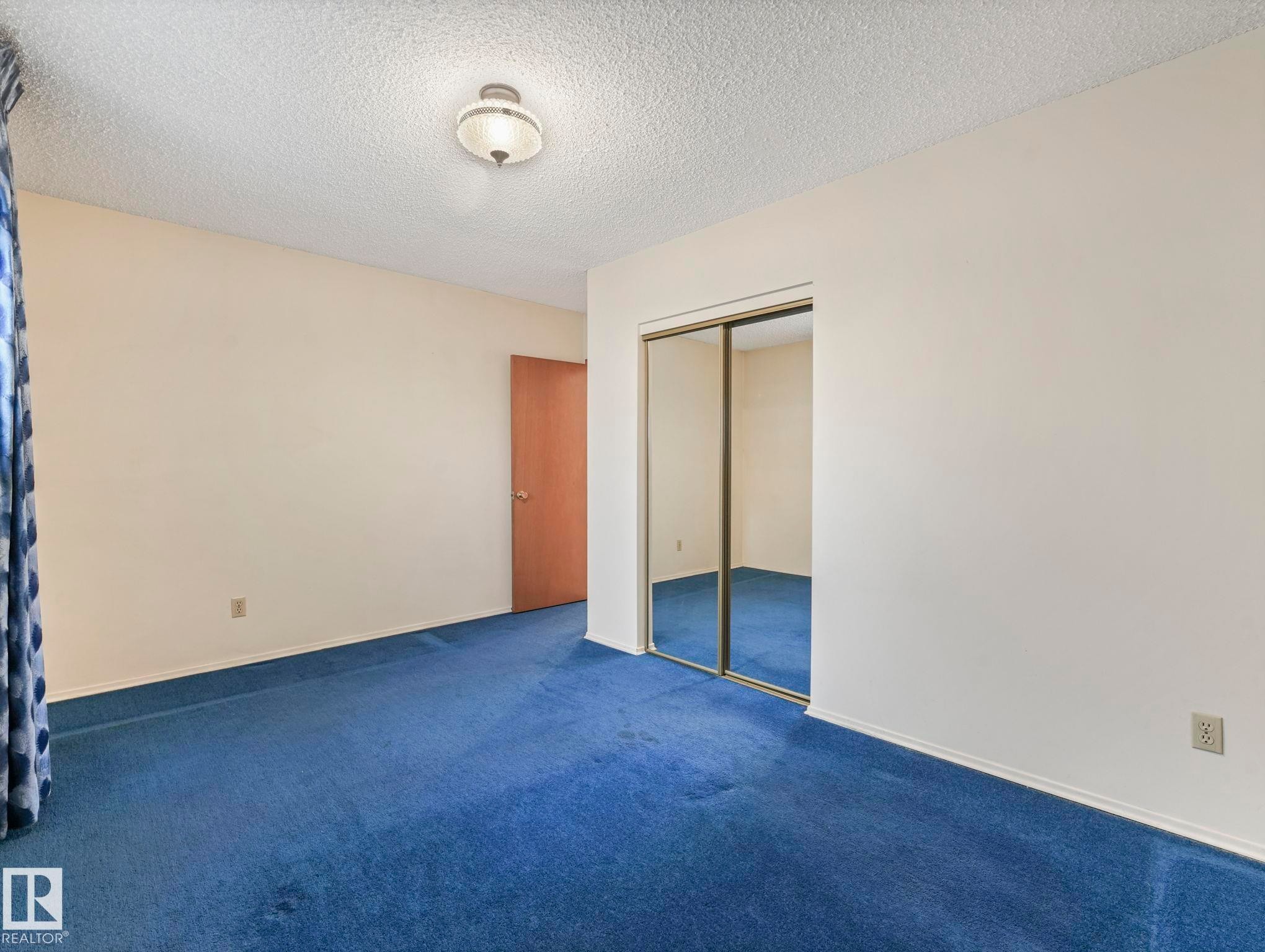 This room features wall-to-wall blue carpeting and a ceiling light fixture - 5904 84 Avenue, Edmonton, AB - Indoor Photo Showing Other Room