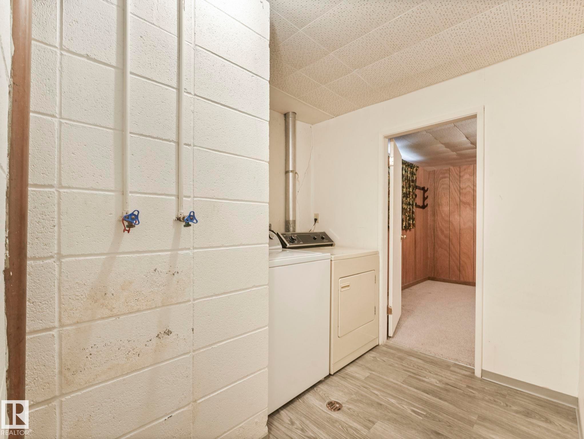 Laundry area with a washer and dryer, featuring light wood-look flooring and a drop ceiling - 5904 84 Avenue, Edmonton, AB - Indoor