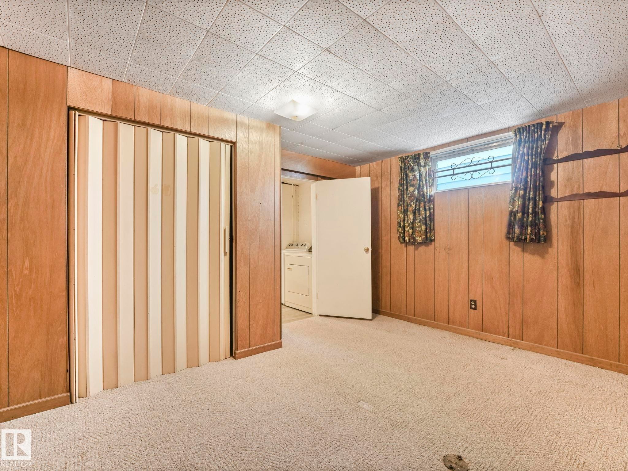 The property features light-colored carpeting, wood paneling on the walls, and a dropped ceiling with square acoustic panels - 5904 84 Avenue, Edmonton, AB - Indoor Photo Showing Other Room