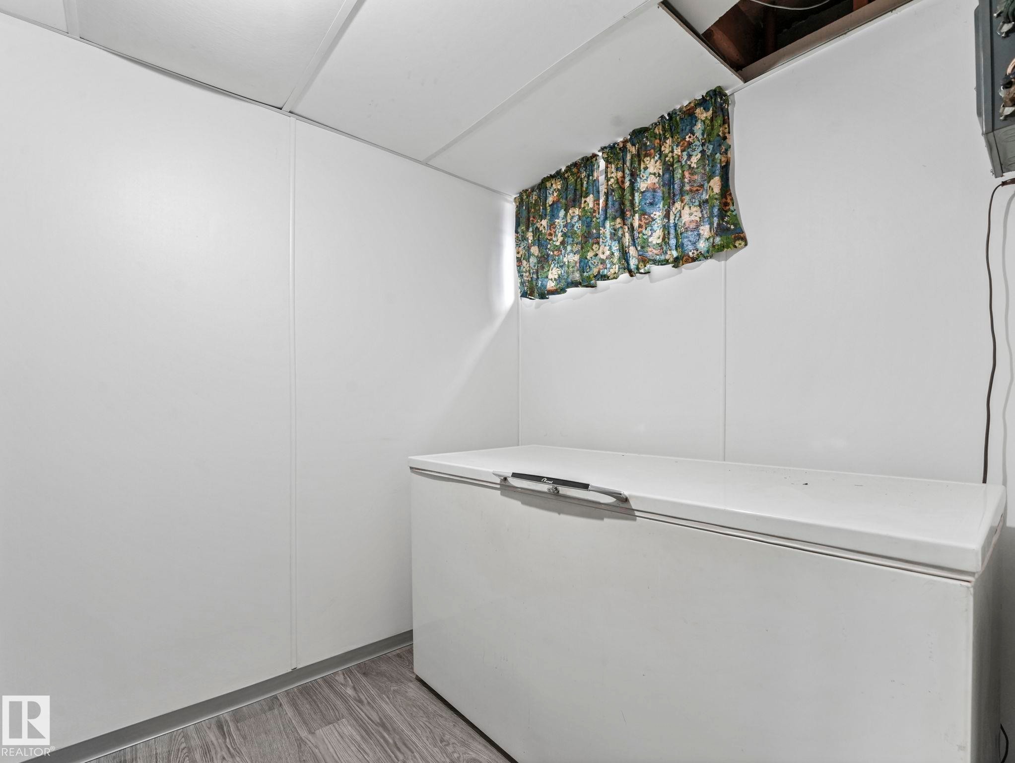 Utility area featuring white walls, a drop ceiling, and wood-look flooring - 5904 84 Avenue, Edmonton, AB - Indoor