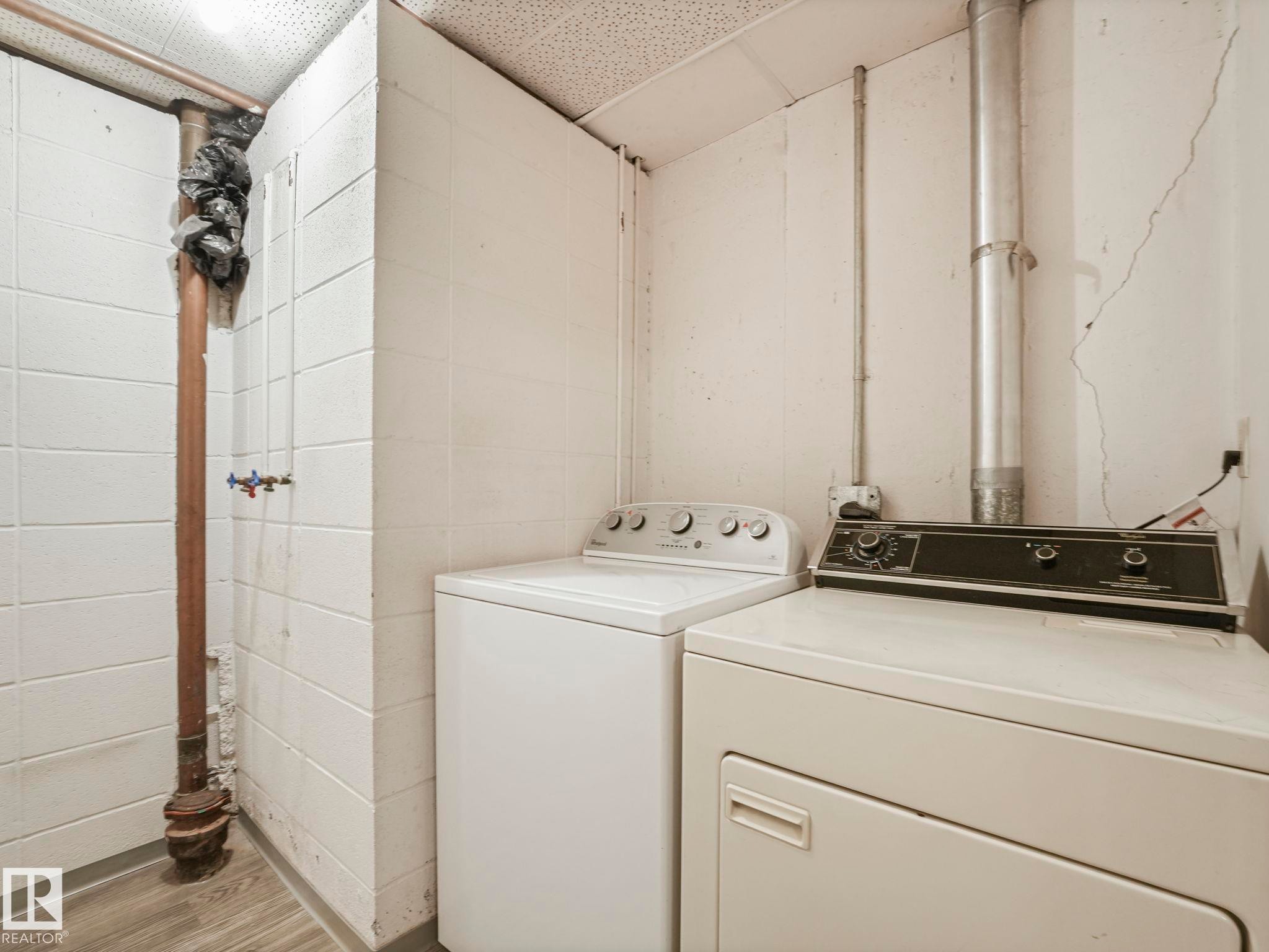 Laundry area featuring a washer and dryer, concrete block walls, and a drop ceiling - 5904 84 Avenue, Edmonton, AB - Indoor Photo Showing Laundry Room