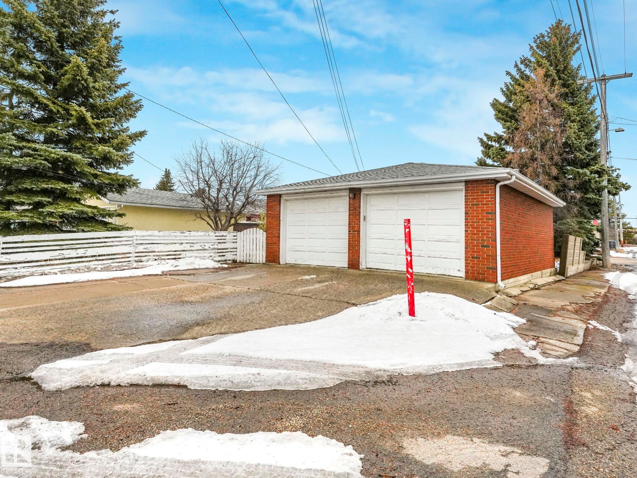 Detached brick garage with two white garage doors and a grey shingled roof - 5904 84 Avenue, Edmonton, AB - Outdoor