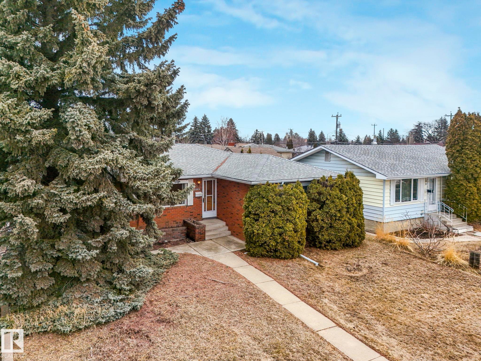 The property features a brick exterior with a white front door and a concrete pathway leading to the entrance - 5904 84 Avenue, Edmonton, AB - Outdoor