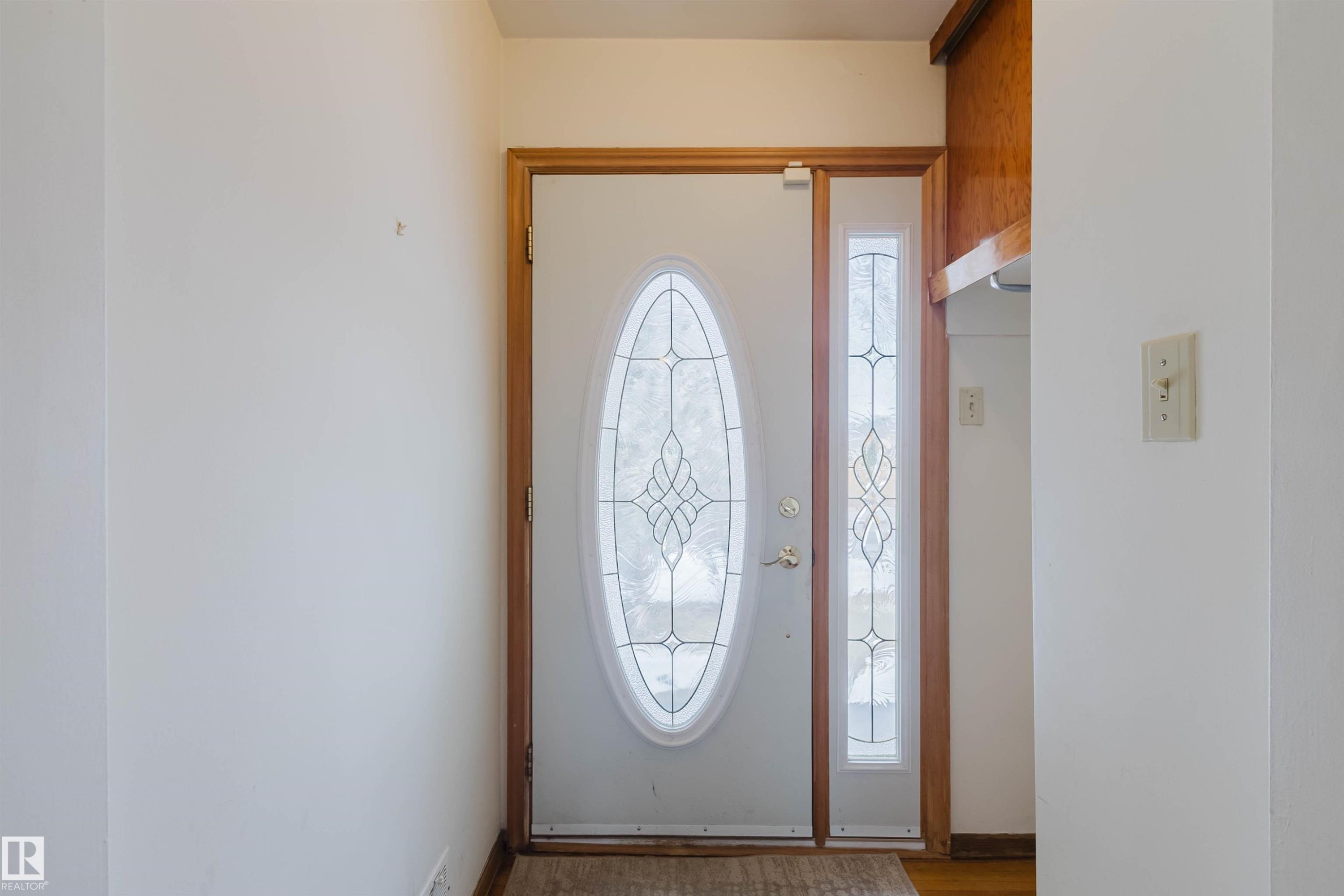The entry features a white door with an oval-shaped decorative glass insert and a coordinating sidelight, framed by light-colored wood trim - 11815 76 Avenue, Edmonton, AB - Indoor Photo Showing Other Room
