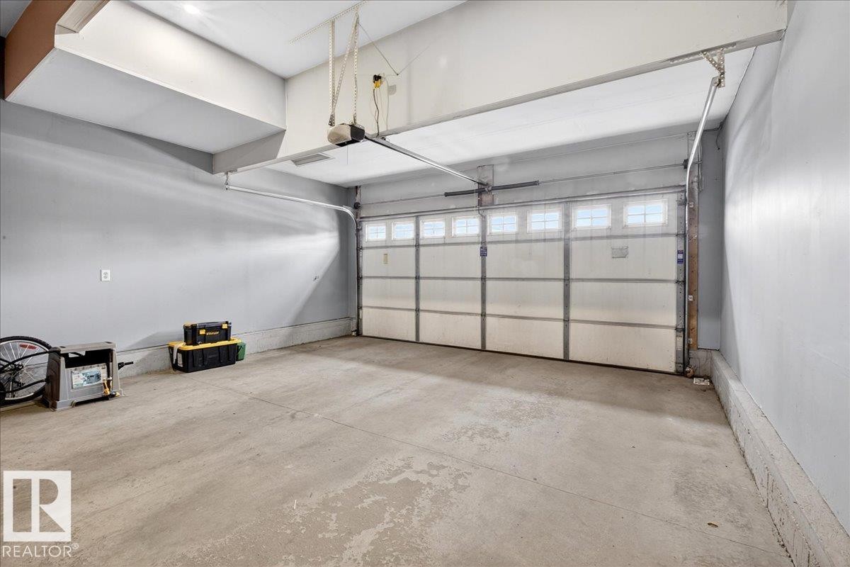 The property features a garage with a concrete floor, light gray walls, and a white garage door with upper window panels - 17023 38 Street Nw, Edmonton, AB - Indoor Photo Showing Garage