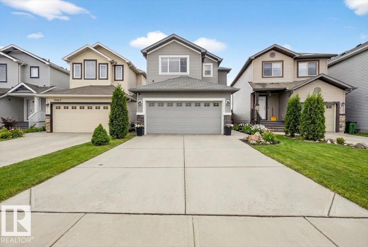 This property features a two-story design with a gray exterior and a prominent front-facing garage - 17023 38 Street Nw, Edmonton, AB - Outdoor With Facade