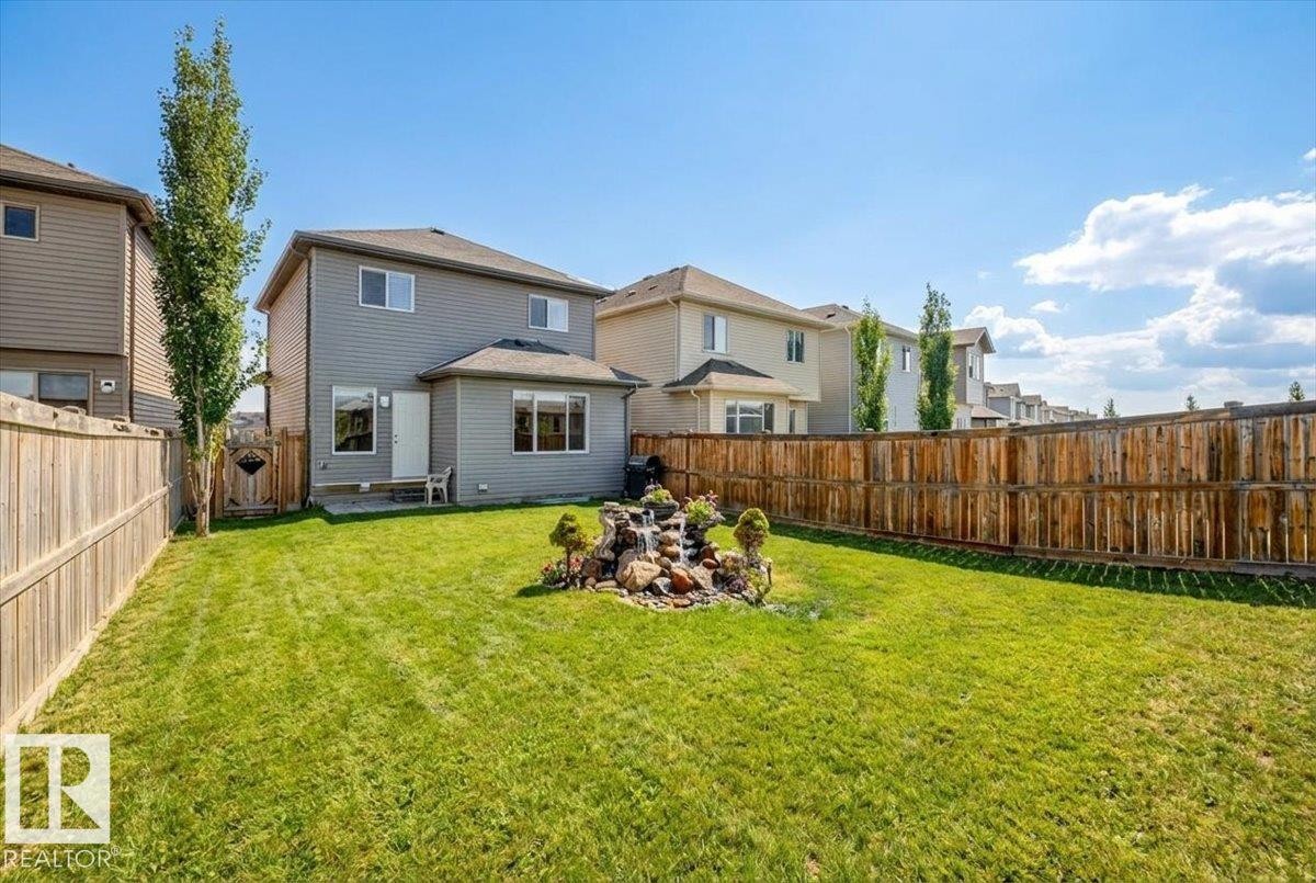The property features an extensive yard with a lawn, a rock garden, and a wooden fence along the perimeter - 17023 38 Street Nw, Edmonton, AB - Outdoor With Backyard