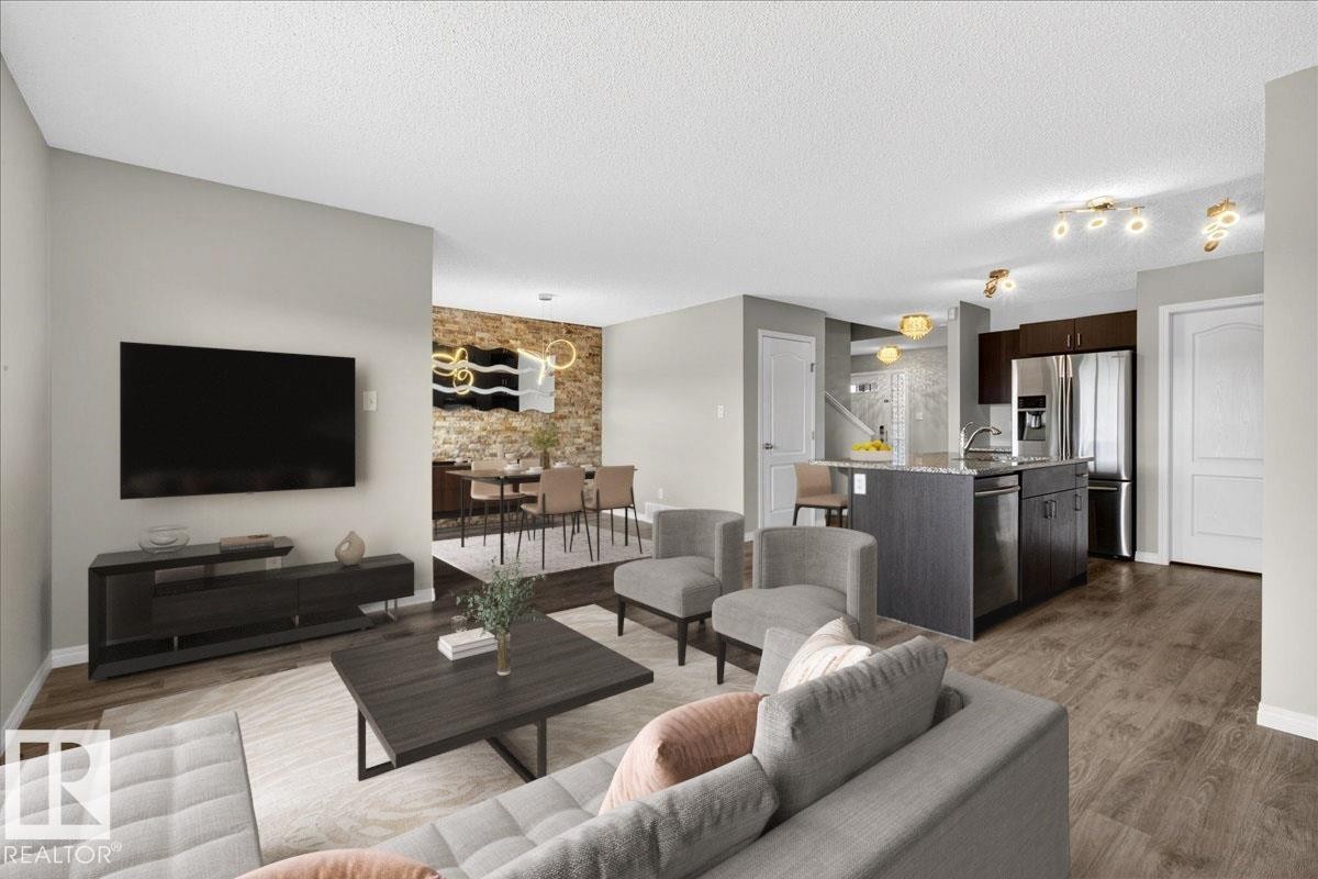 The property features an open concept living area with hardwood flooring, a dining area with a stone accent wall, and a kitchen with an island and stainless steel appliances (furniture is stage for the photo) - 17023 38 Street Nw, Edmonton, AB - Indoor Photo Showing Living Room