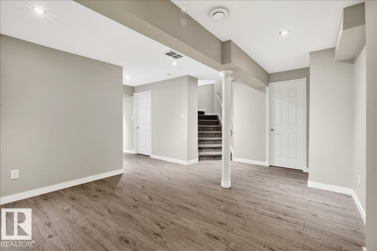 Spacious area featuring wood-look flooring, light-colored walls, and recessed lighting - 17023 38 Street Nw, Edmonton, AB - Indoor Photo Showing Other Room
