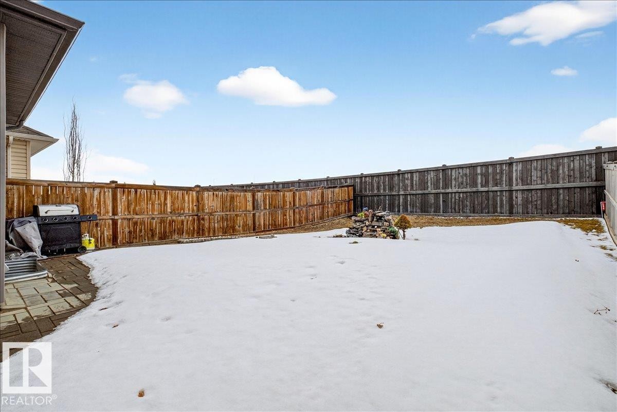 The property features a spacious backyard with a paved patio area, surrounded by a wooden fence - 17023 38 Street Nw, Edmonton, AB - Outdoor