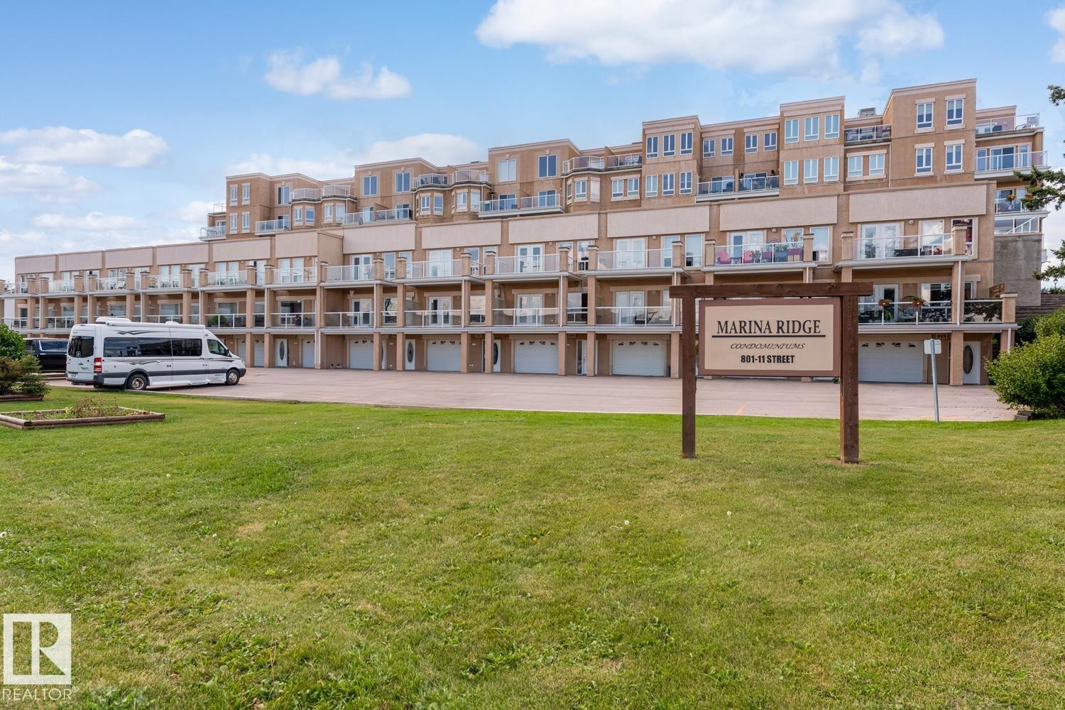 Exterior view of the property, featuring a multi-story building with balconies and individual garages - 107 801 11 Street, Cold Lake, AB - Outdoor