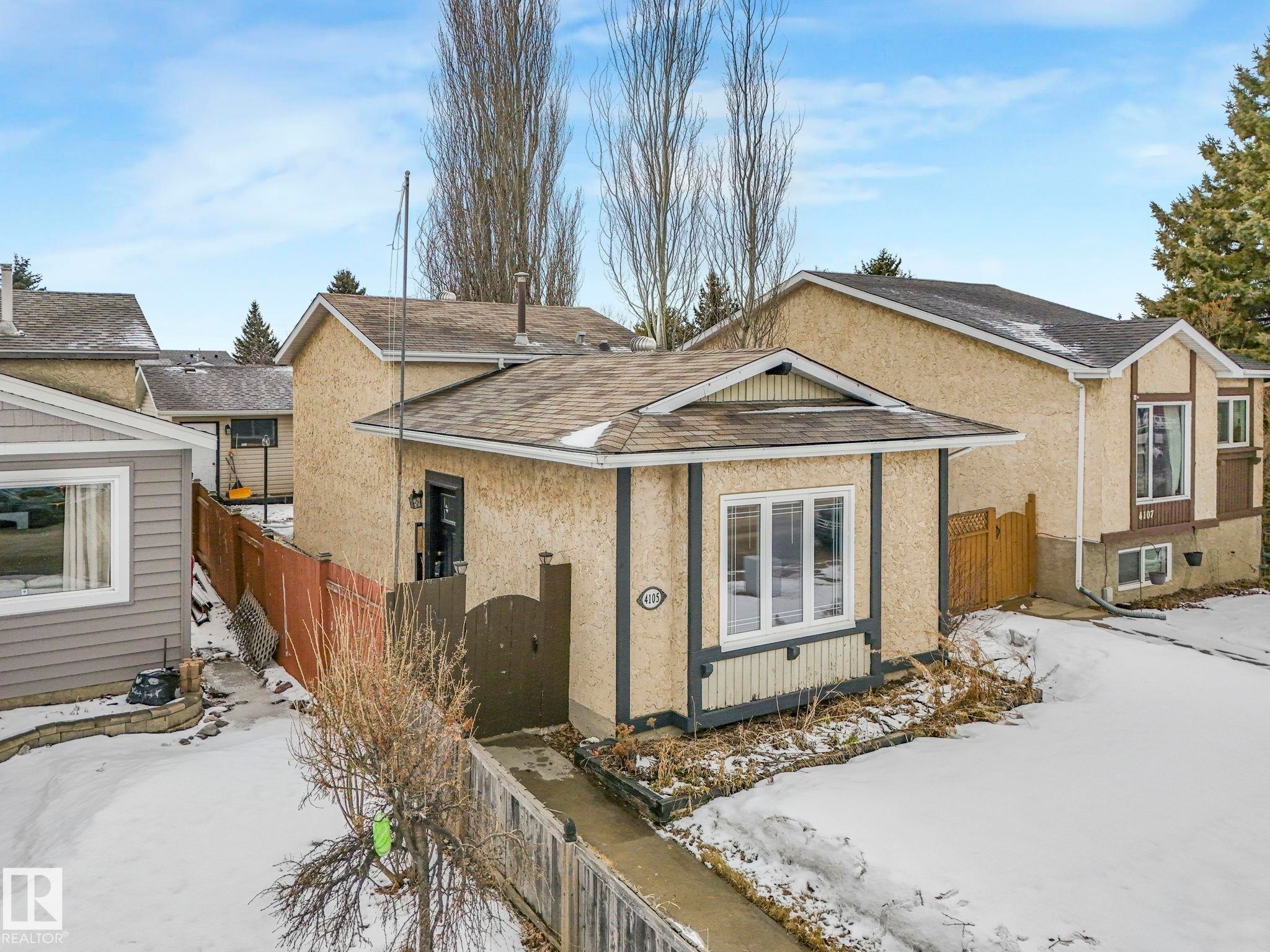 The property features a stucco exterior with dark trim accents and white-framed windows - 4105 41 Avenue, Edmonton, AB - Outdoor