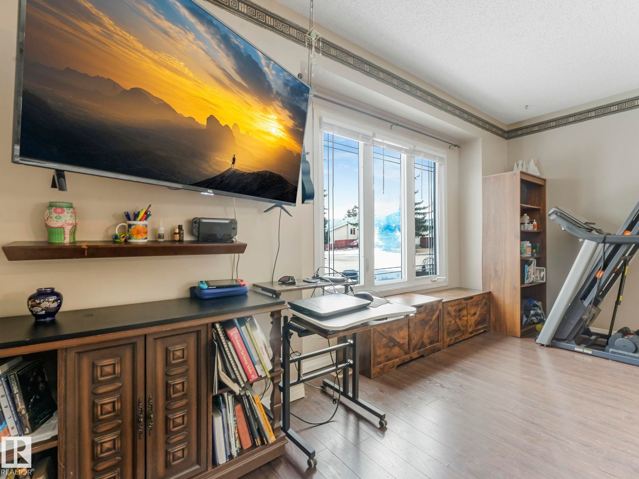 Room featuring light-colored walls, wood-style flooring, a large window, and a built-in wooden storage bench - 4105 41 Avenue, Edmonton, AB - Indoor