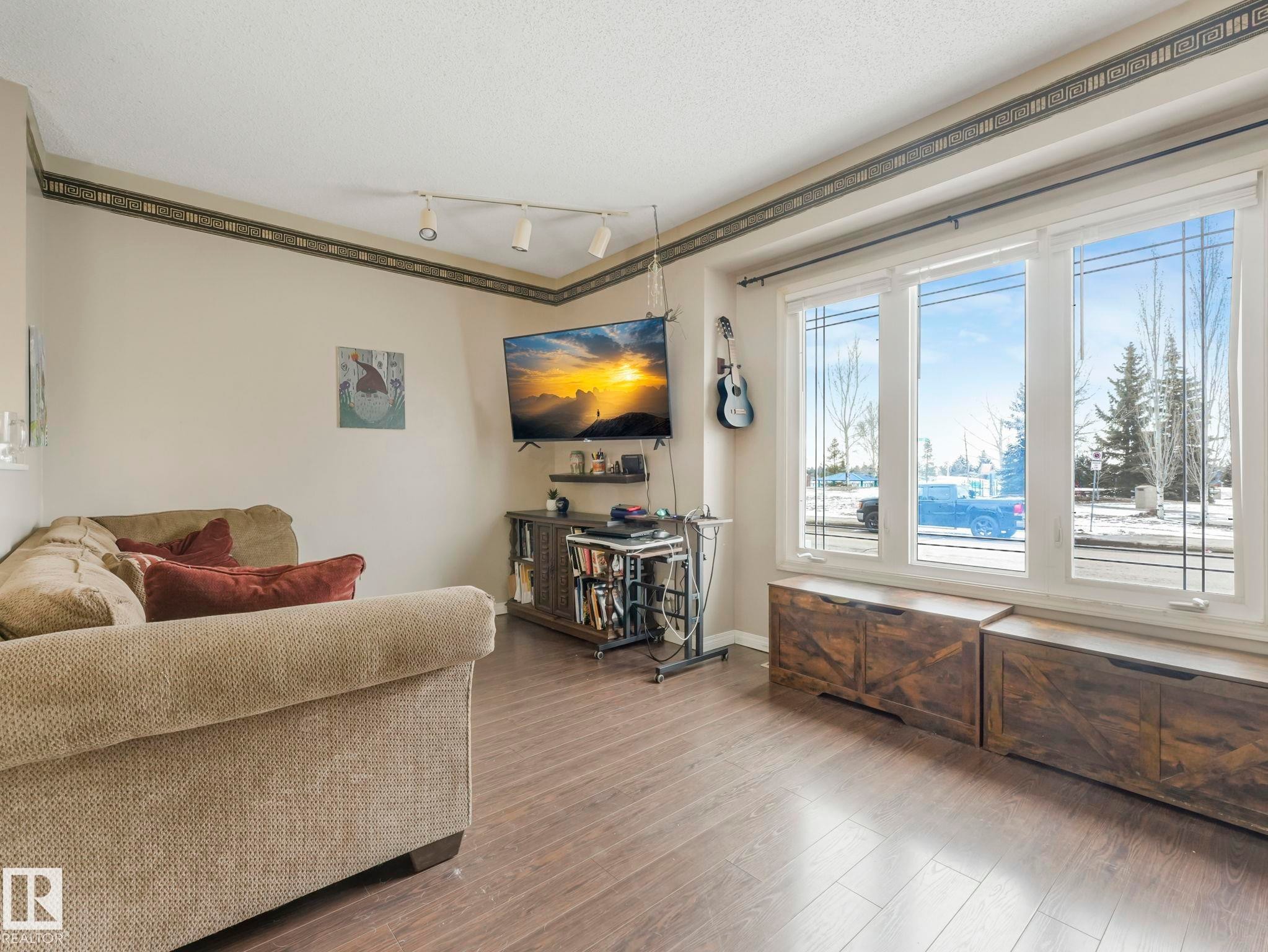 Living area featuring wood-look flooring, large windows, and track lighting - 4105 41 Avenue, Edmonton, AB - Indoor