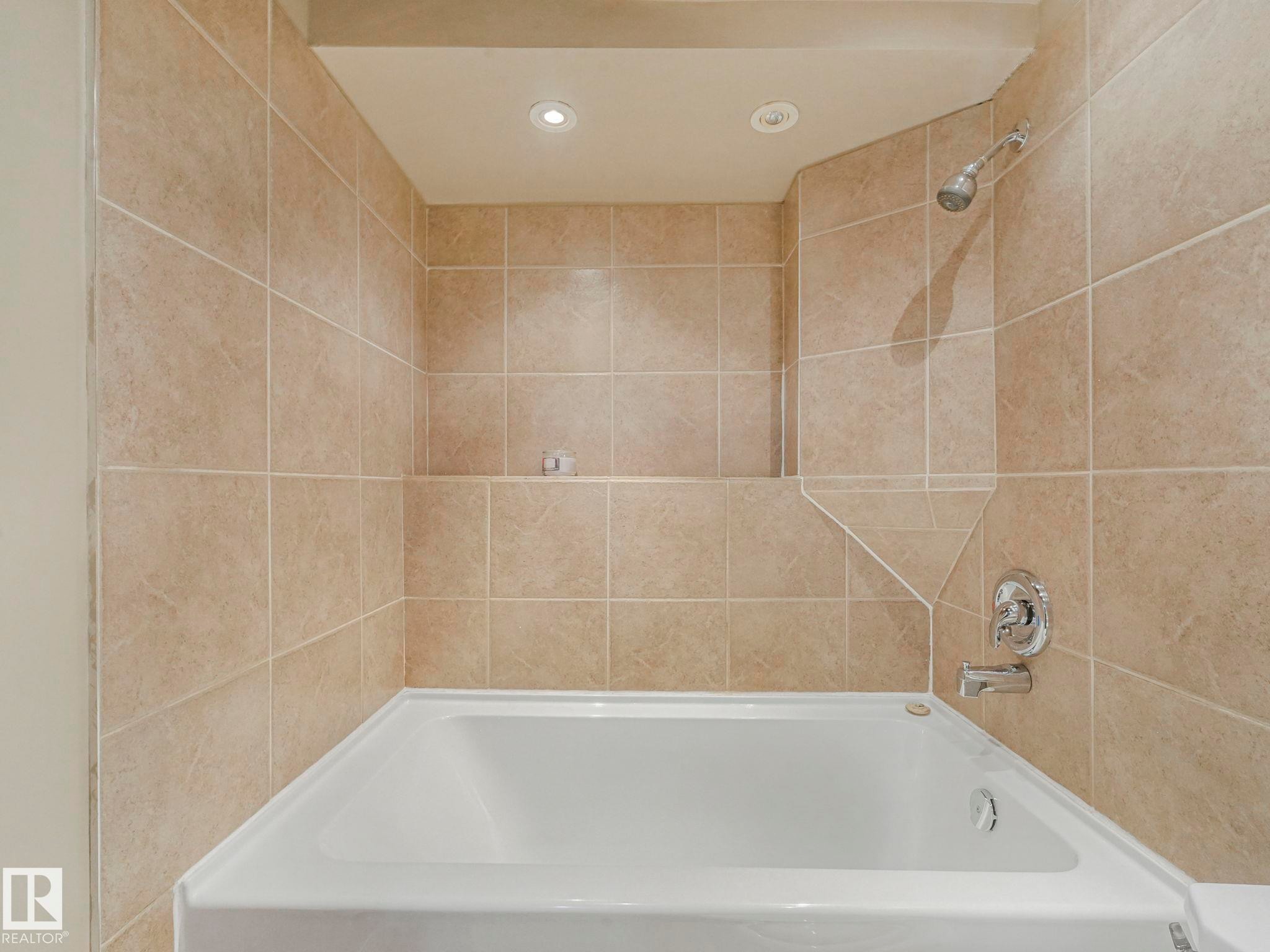 Bathroom featuring a white bathtub, tiled walls, a shower fixture, and recessed lighting - 4105 41 Avenue, Edmonton, AB - Indoor Photo Showing Bathroom