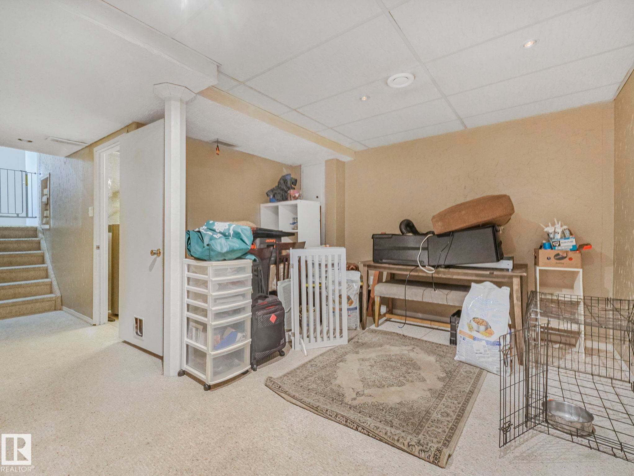 The property features a carpeted room with a staircase, a white door, and neutral-toned walls - 4105 41 Avenue, Edmonton, AB - Indoor Photo Showing Other Room