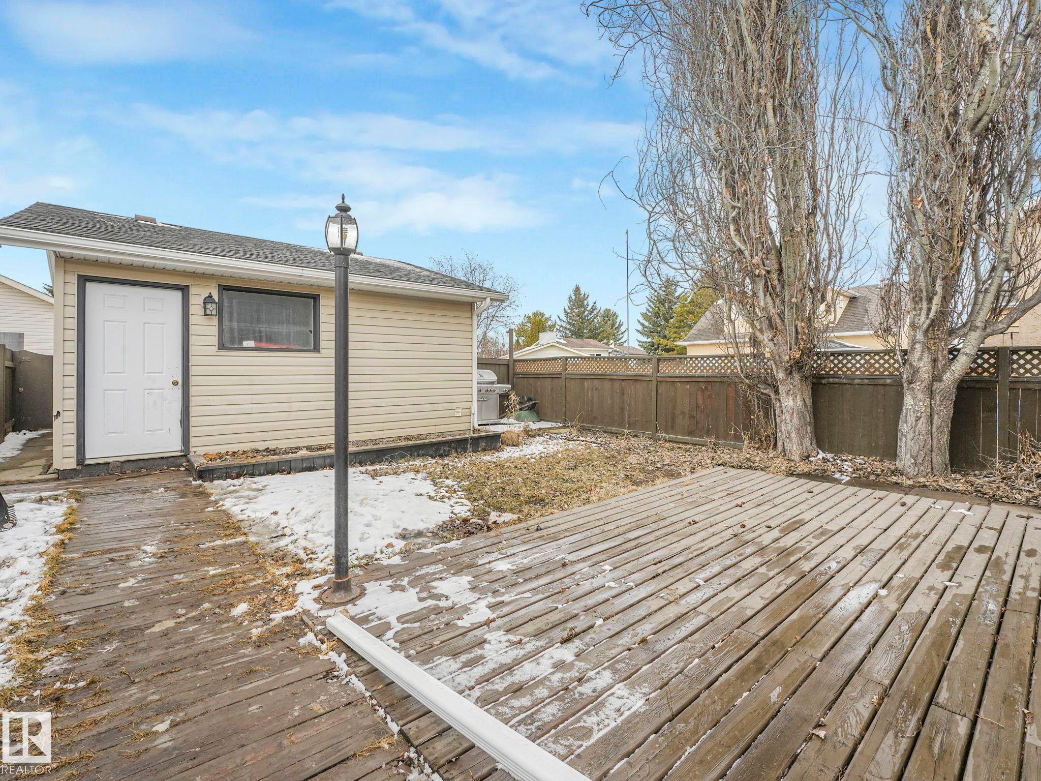 The property features a spacious yard with a wooden deck and a detached outbuilding, offering versatile outdoor space - 4105 41 Avenue, Edmonton, AB - Outdoor