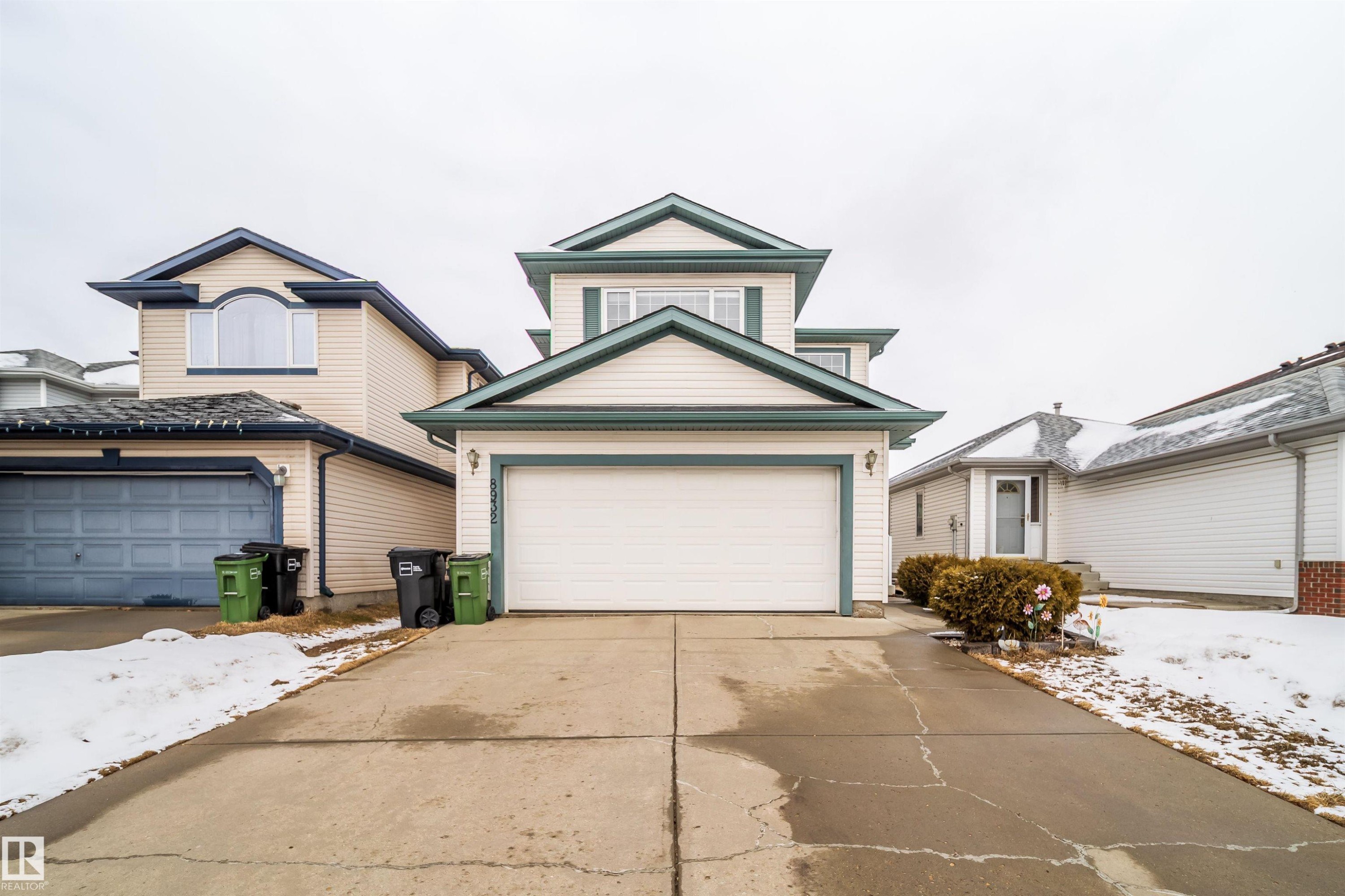 The property features a two-story exterior with light-colored siding and dark trim, a front-facing garage, and a concrete driveway - 8932 175 Avenue, Edmonton, AB - Outdoor With Facade