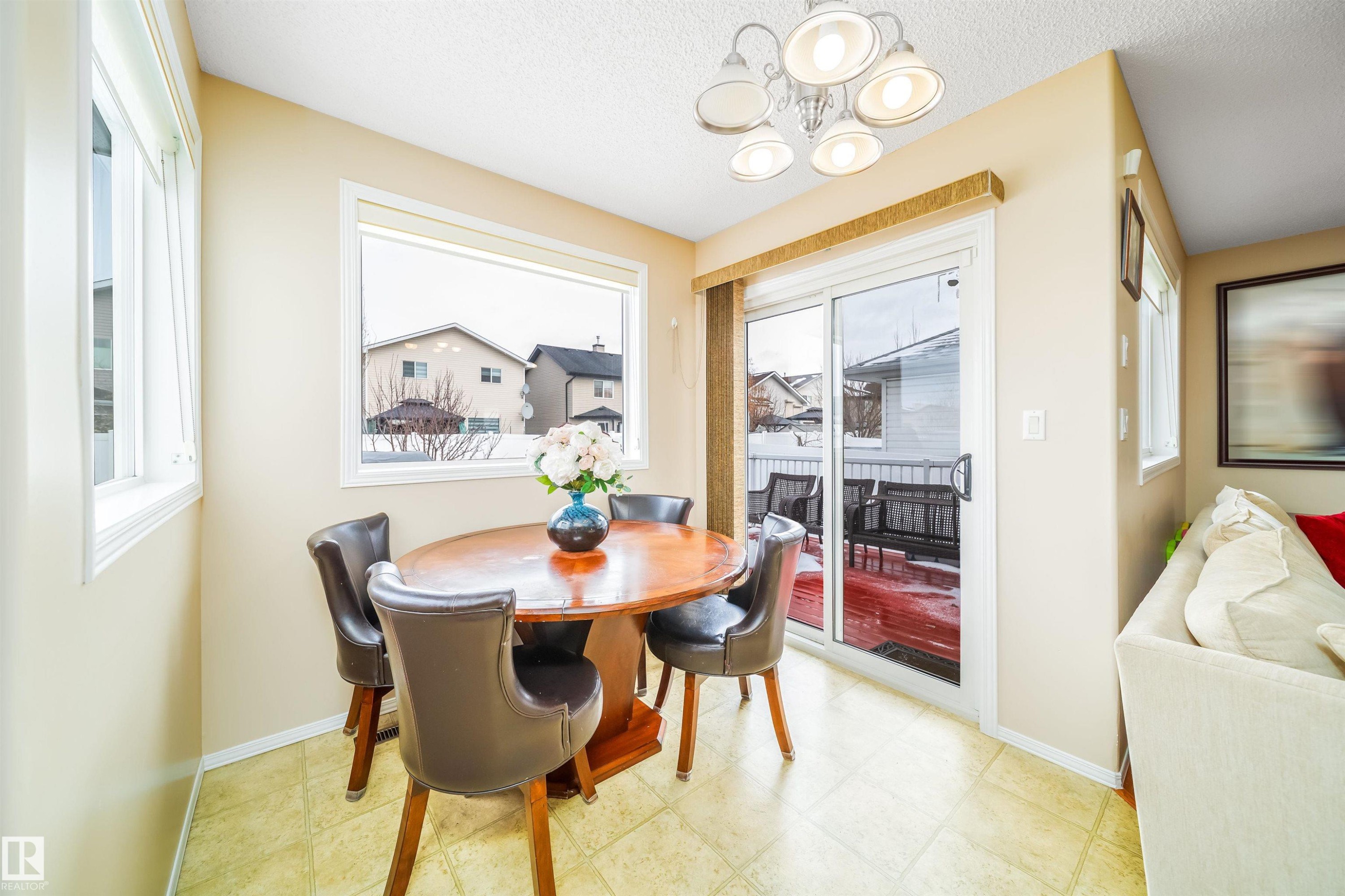 This dining area features a bright and open layout with ample natural light from two windows and a glass sliding door - 8932 175 Avenue, Edmonton, AB - Indoor Photo Showing Dining Room