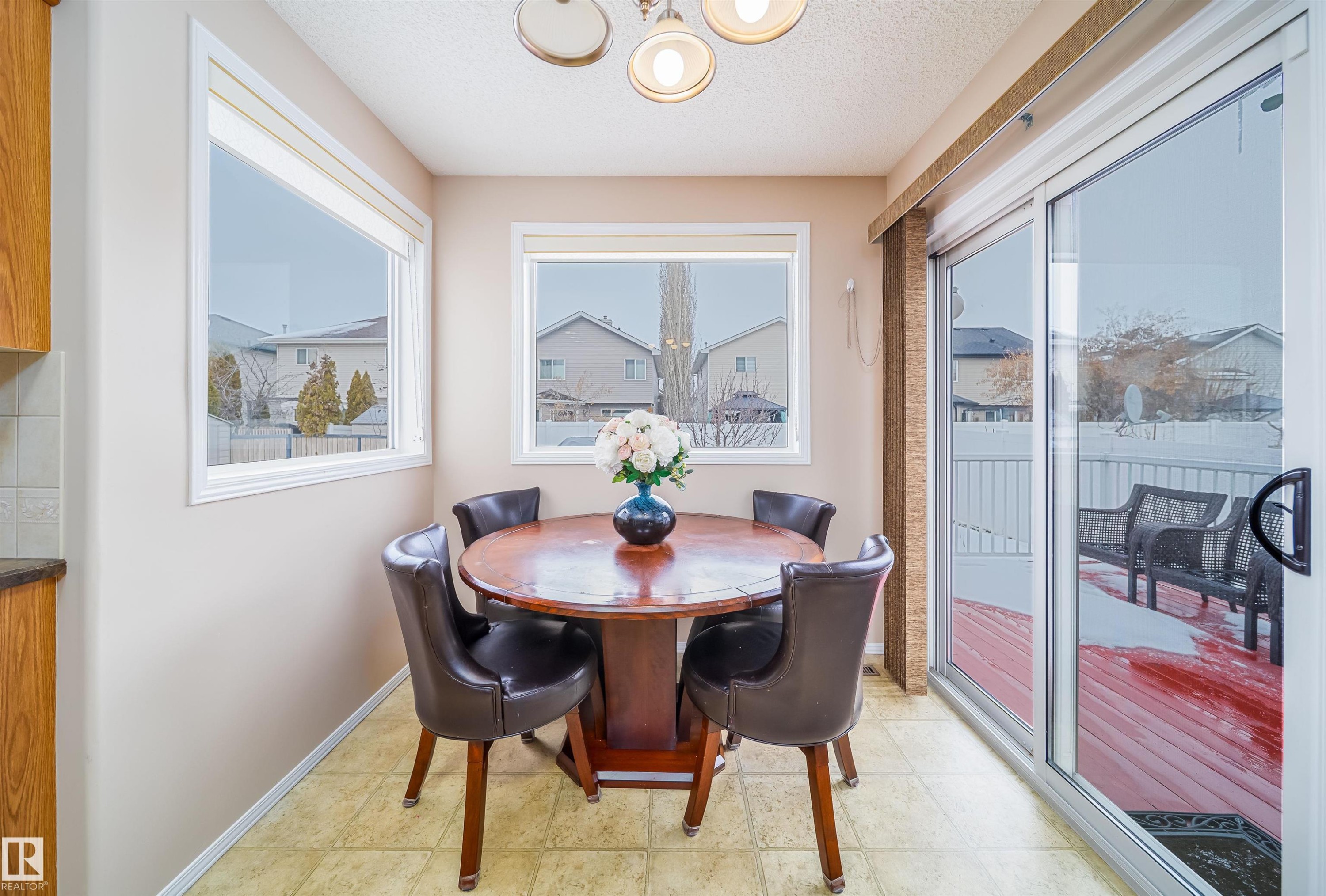 This dining area features light-colored walls, multiple windows, and a sliding glass door providing direct access to a deck - 8932 175 Avenue, Edmonton, AB - Indoor Photo Showing Dining Room