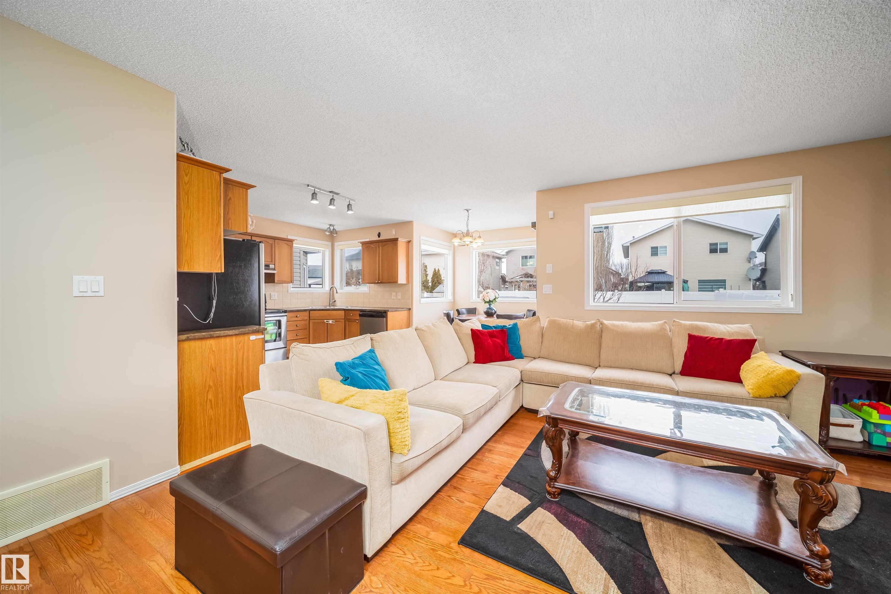 The property features an open-concept living area with hardwood flooring, a large window providing natural light, and recessed lighting in the kitchen area - 8932 175 Avenue, Edmonton, AB - Indoor Photo Showing Living Room