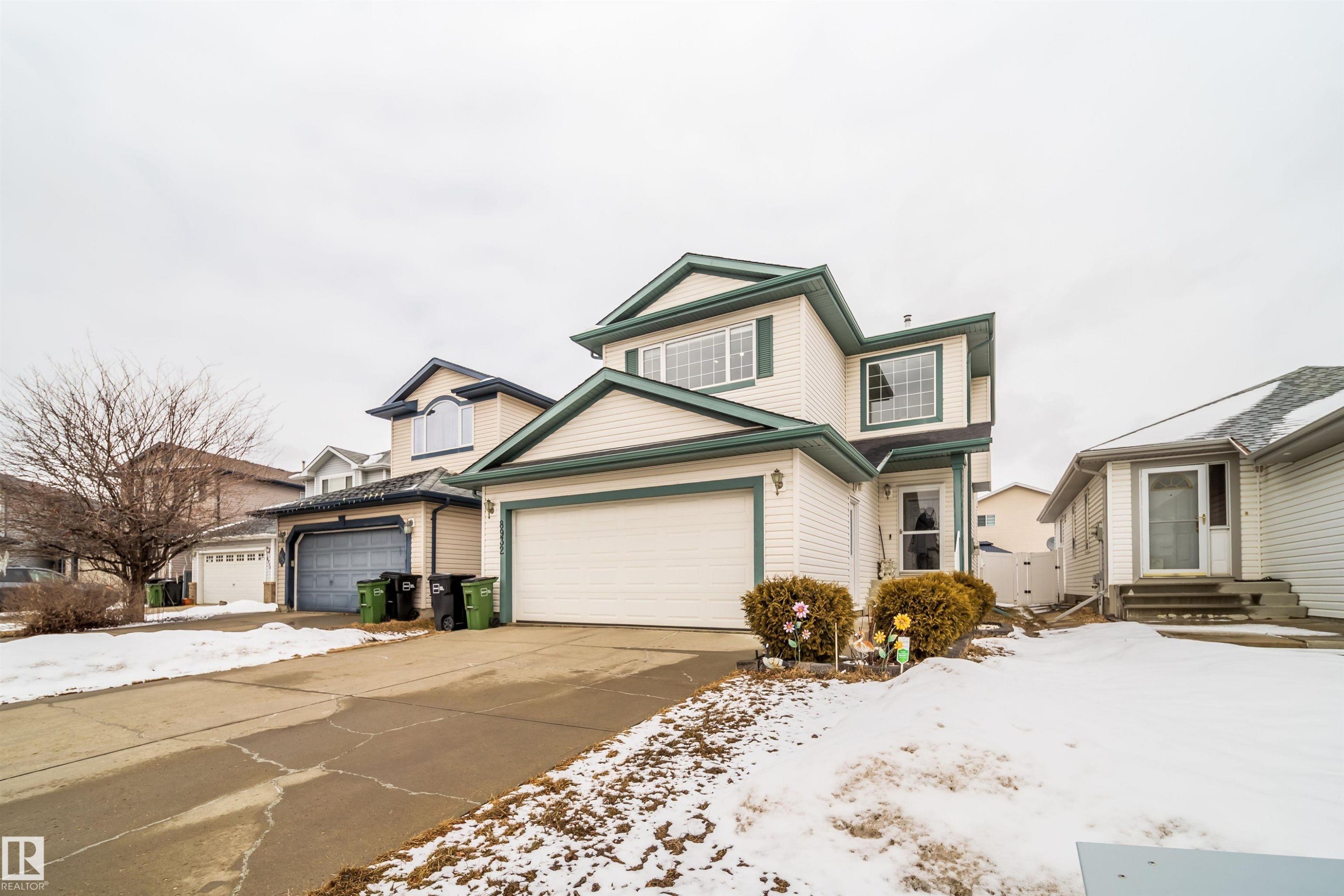 This property features light-colored siding with dark trim, a two-car garage, and an additional single-car garage - 8932 175 Avenue, Edmonton, AB - Outdoor With Facade