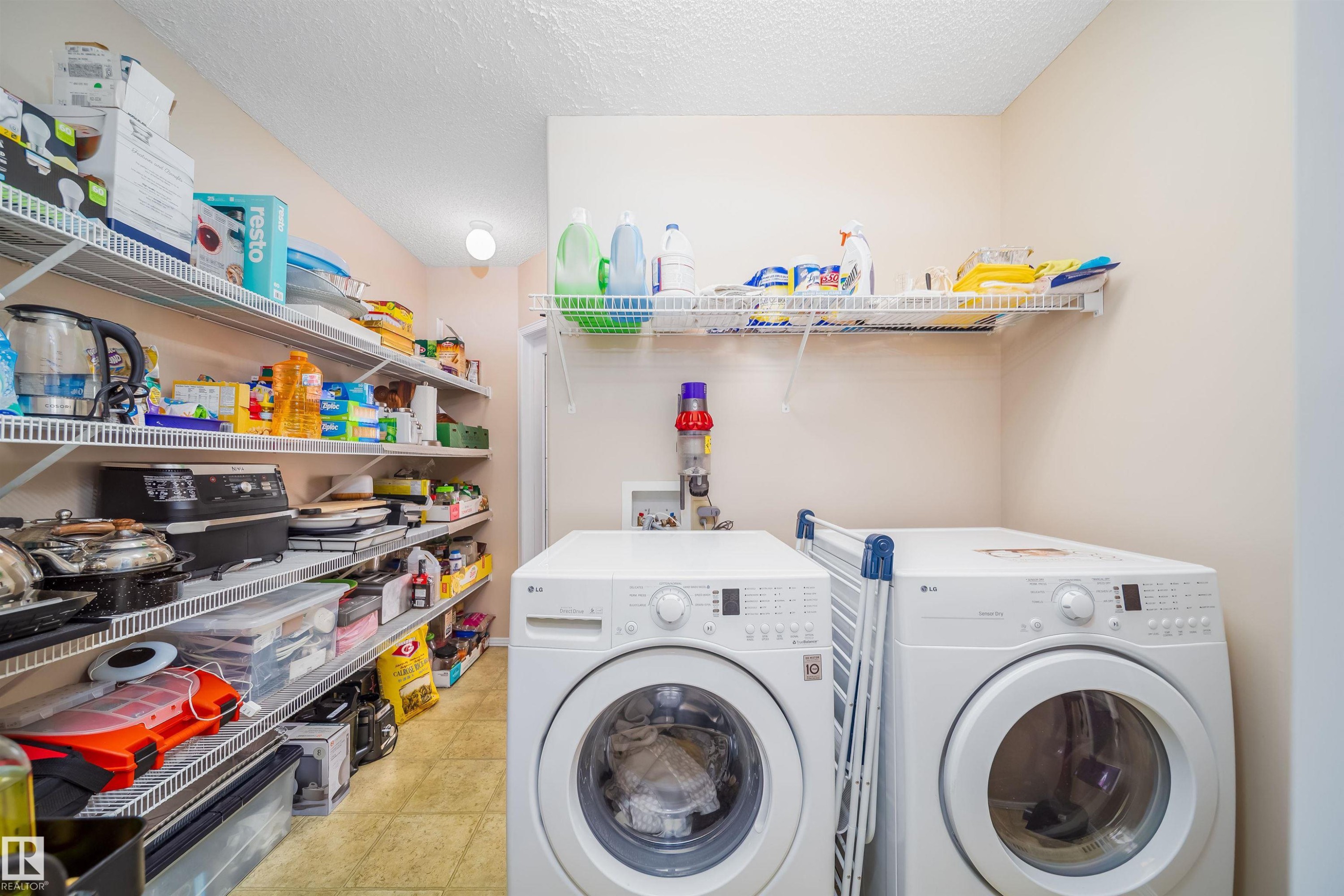Functional utility area featuring a washer and dryer, wire shelving, and overhead lighting - 8932 175 Avenue, Edmonton, AB - Indoor Photo Showing Laundry Room