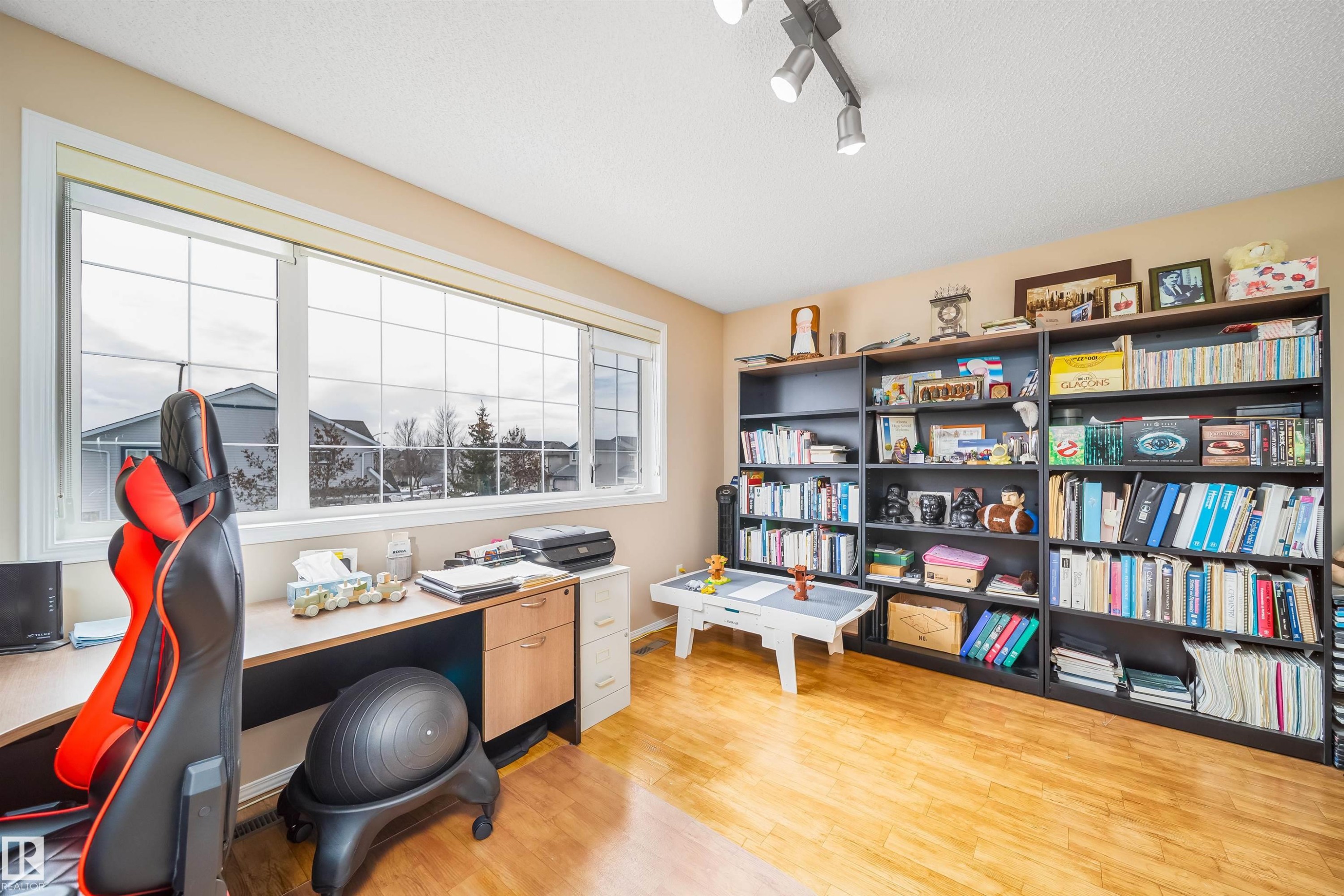 This versatile room features light-toned hardwood flooring and a large window providing natural light - 8932 175 Avenue, Edmonton, AB - Indoor Photo Showing Office