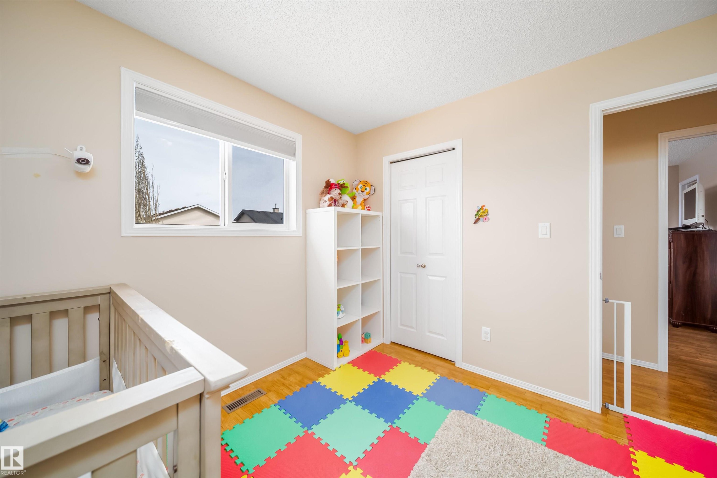 This room features a window providing natural light, a closet with a white bi-fold door, and hardwood flooring - 8932 175 Avenue, Edmonton, AB - Indoor