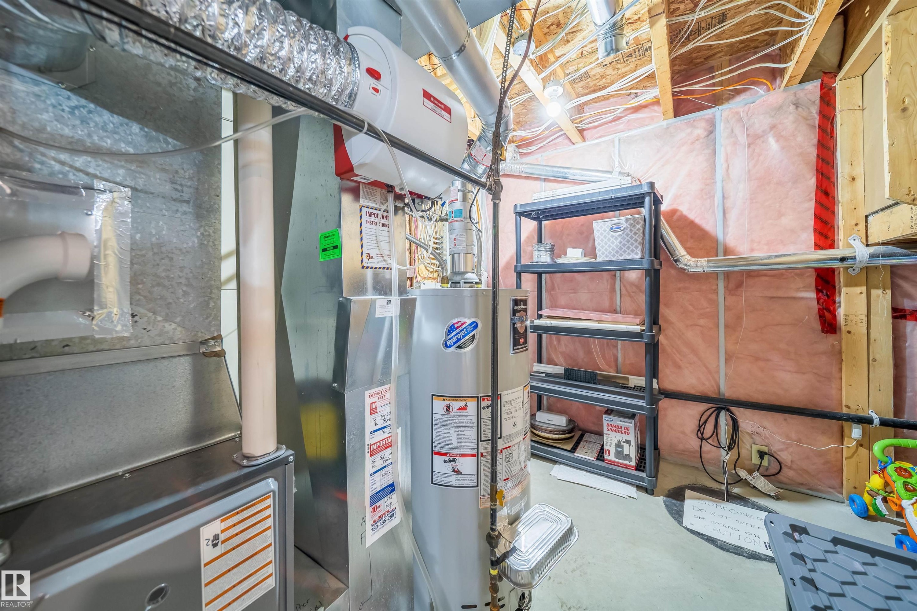 Utility area featuring exposed wooden joists, insulated walls, and a water heater - 8932 175 Avenue, Edmonton, AB - Indoor Photo Showing Basement