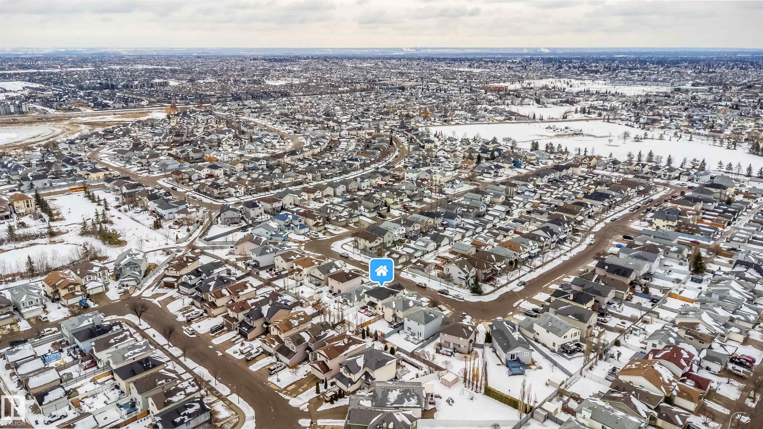 Aerial view of the surrounding residential neighborhood with snow-covered grounds and streets, featuring a nearby body of water - 8932 175 Avenue, Edmonton, AB - Outdoor With View
