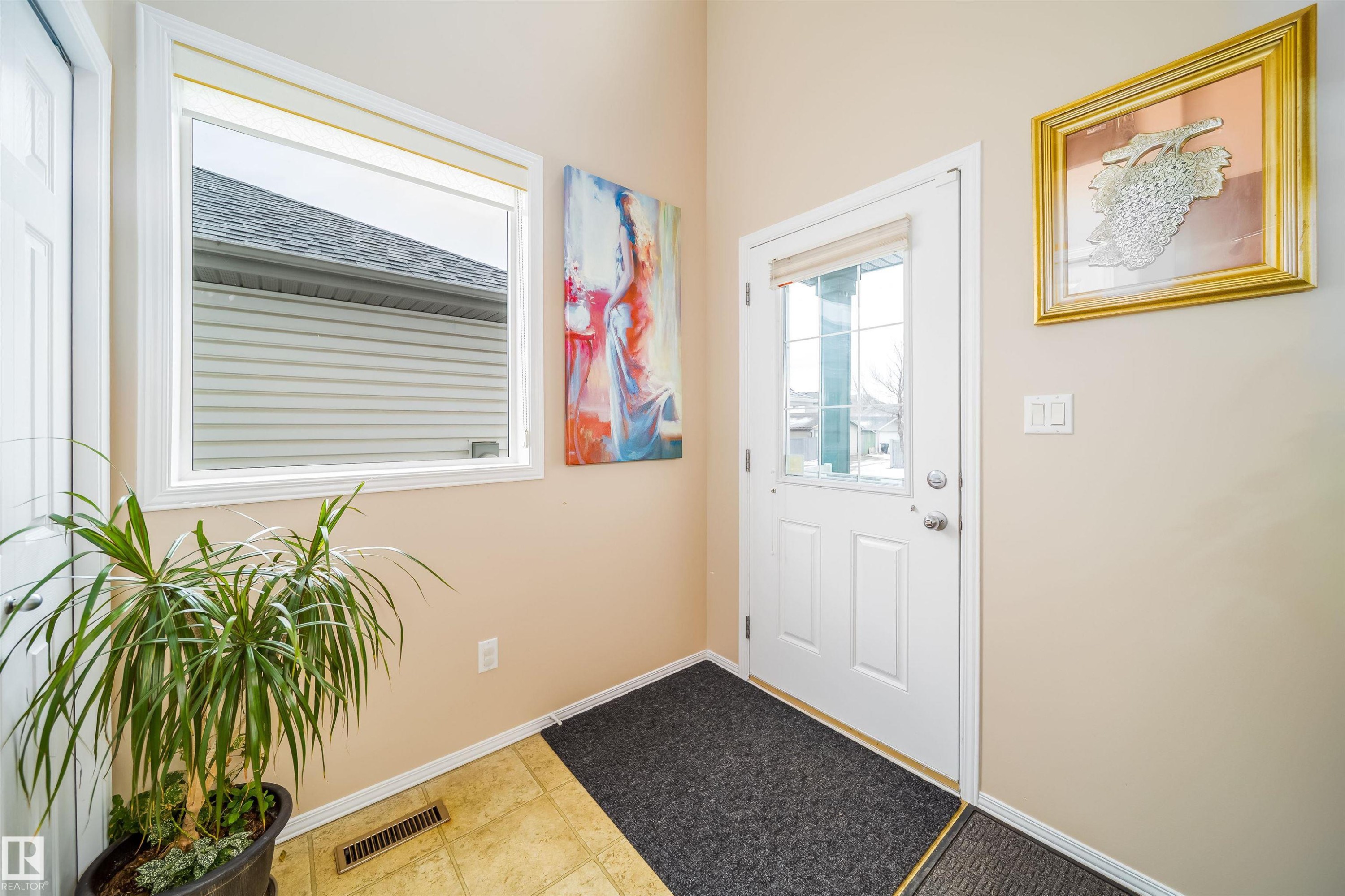 The property features a front door with a window inset, a large window, and light-colored walls - 8932 175 Avenue, Edmonton, AB - Indoor Photo Showing Other Room