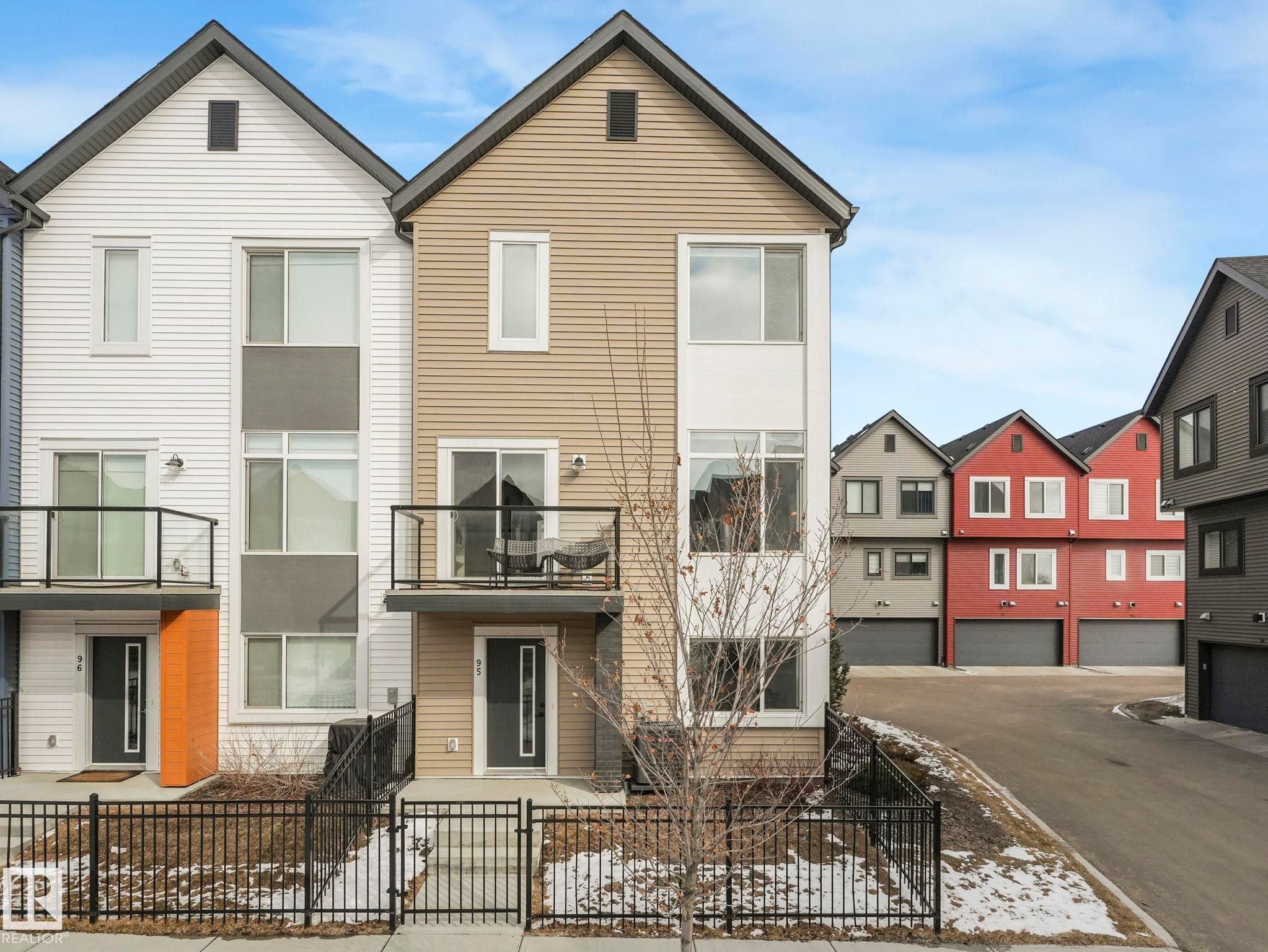 The property features a multi-story exterior with a balcony, a front fence, and a front entry door - 95 1010 Rabbit Hill Road, Edmonton, AB - Outdoor With Facade