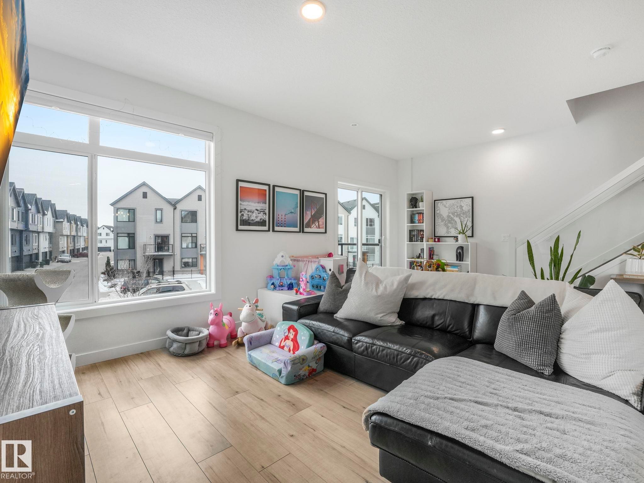 Living space featuring light-toned flooring, large windows, and white walls - 95 1010 Rabbit Hill Road, Edmonton, AB - Indoor Photo Showing Living Room