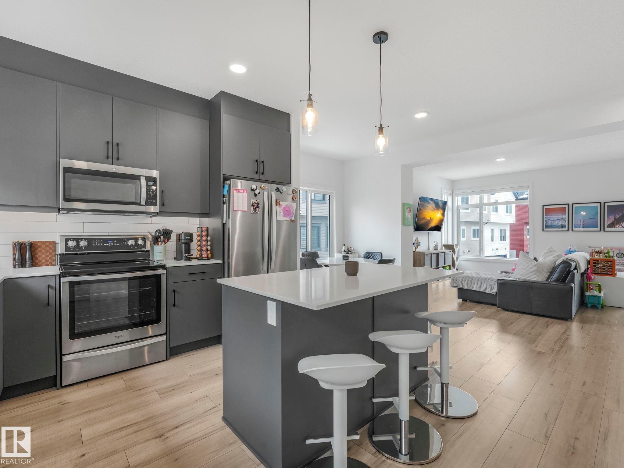 Modern kitchen featuring dark grey cabinetry, stainless steel appliances, and a central island with a light-colored countertop - 95 1010 Rabbit Hill Road, Edmonton, AB - Indoor Photo Showing Kitchen With Upgraded Kitchen