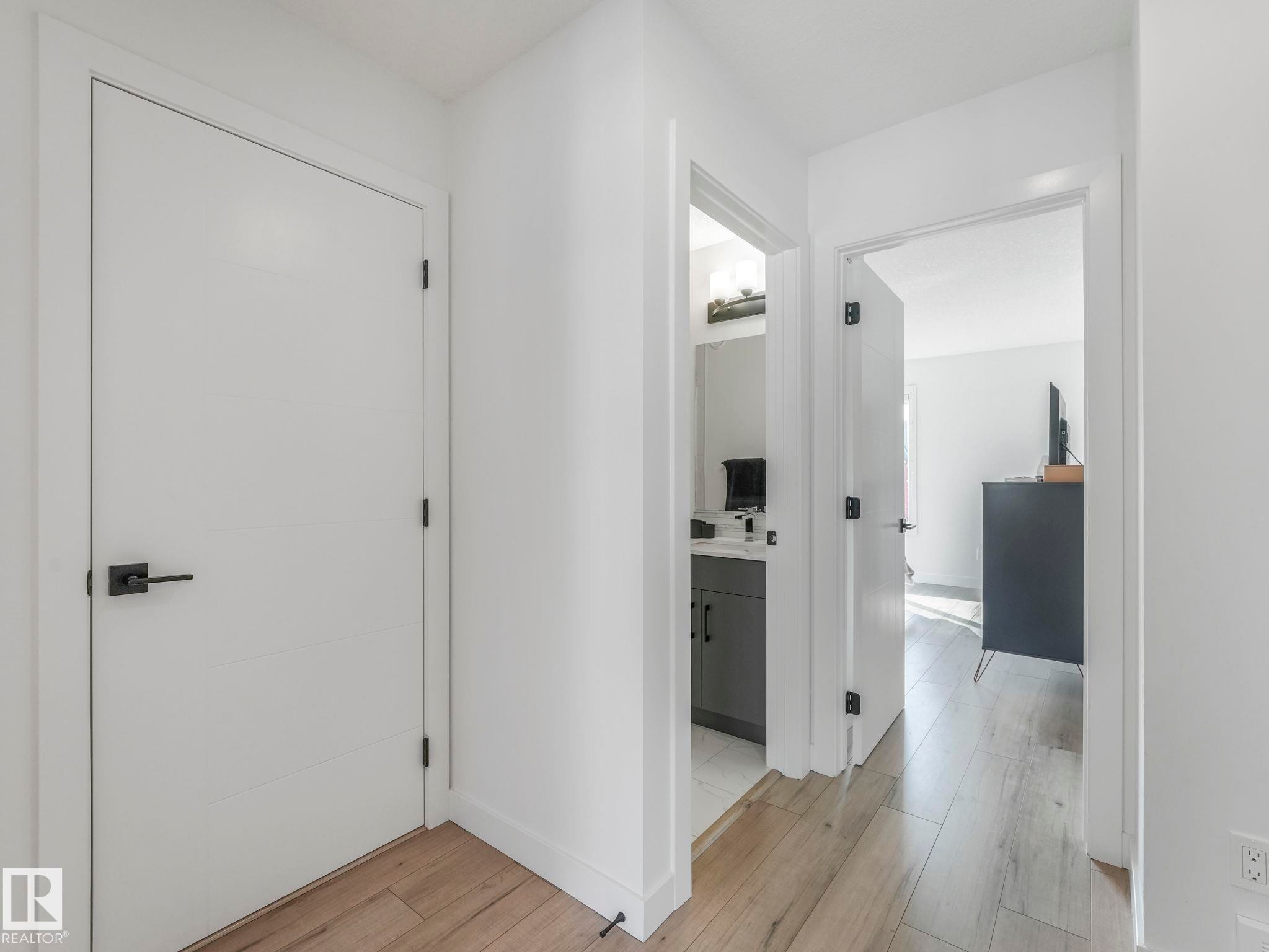 The property features light wood flooring and white walls, with entrances to rooms featuring modern white doors and matte black hardware - 95 1010 Rabbit Hill Road, Edmonton, AB - Indoor Photo Showing Other Room