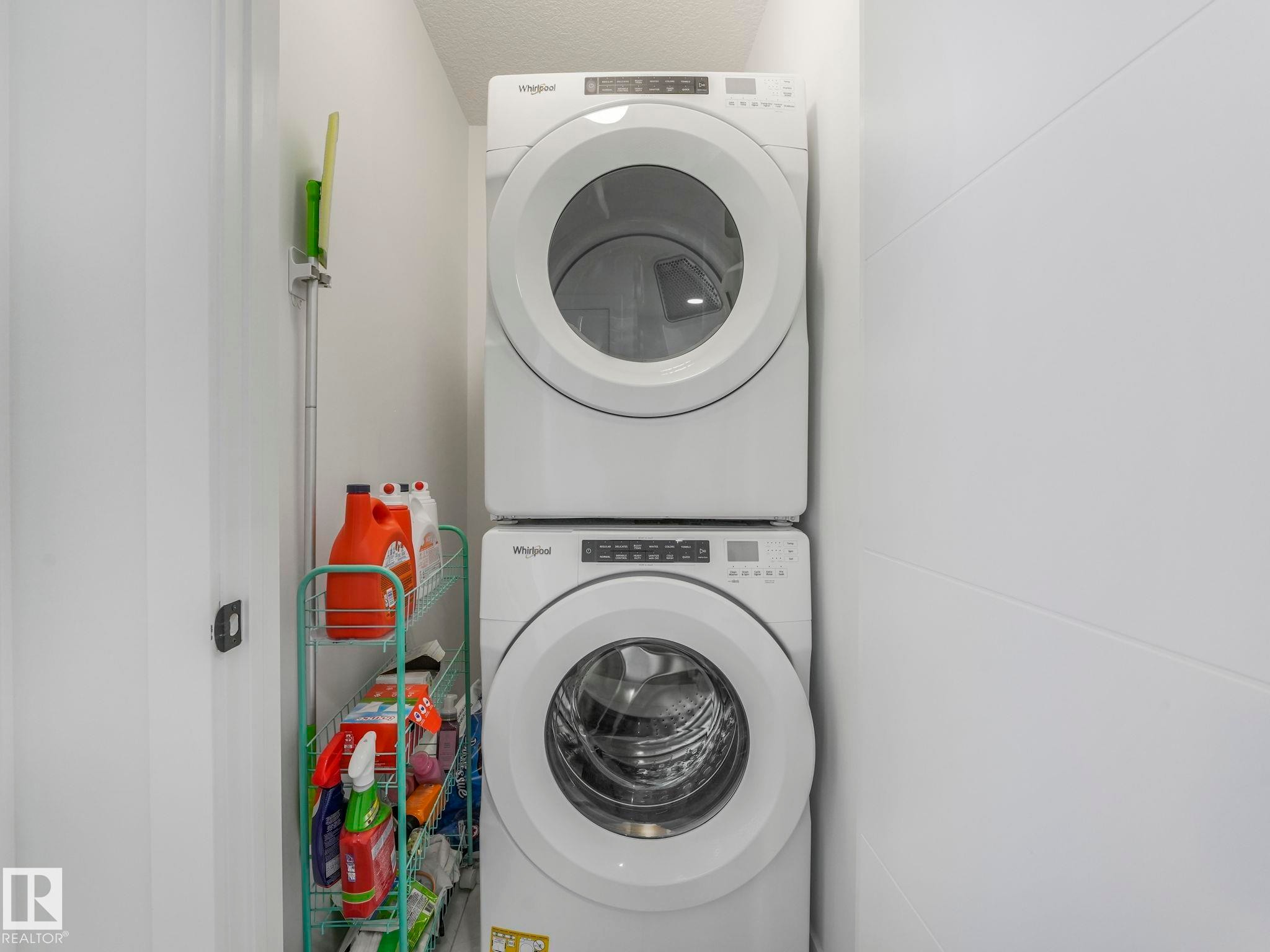 Dedicated laundry area featuring a white stacked washer and dryer unit - 95 1010 Rabbit Hill Road, Edmonton, AB - Indoor Photo Showing Laundry Room