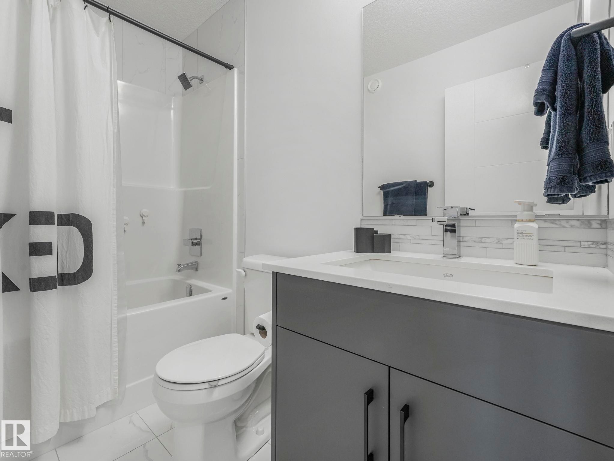 Bathroom featuring a modern vanity with a white countertop, a rectangular sink, and a large mirror - 95 1010 Rabbit Hill Road, Edmonton, AB - Indoor Photo Showing Bathroom