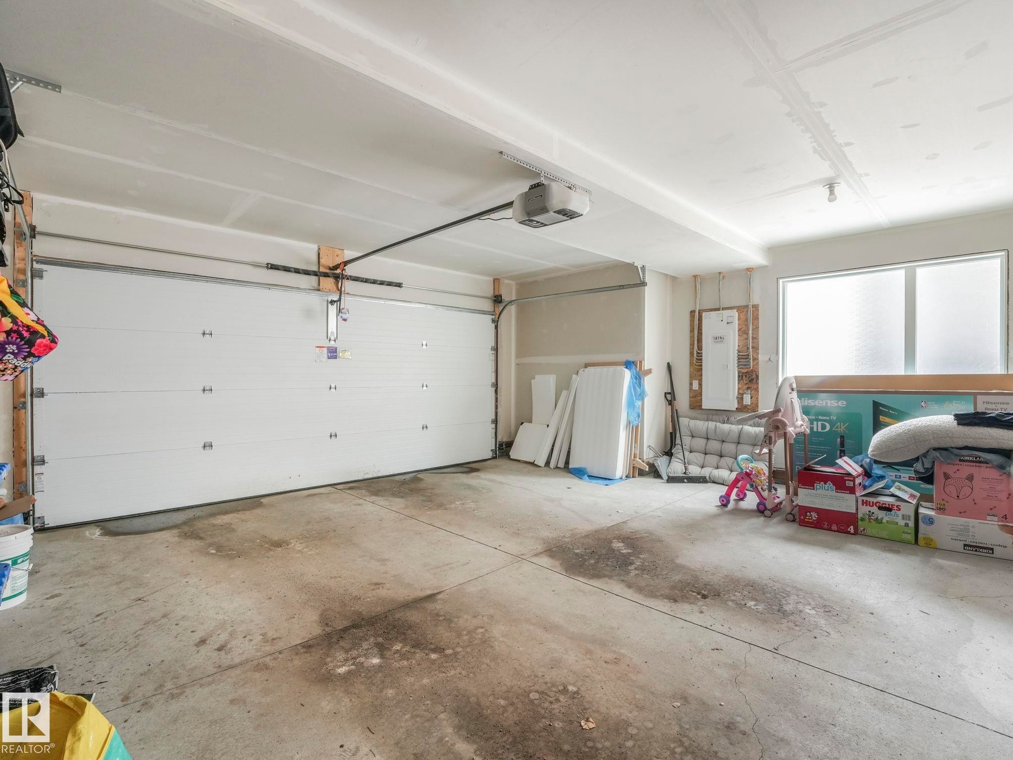 The property features a garage with a white overhead door and an automatic opener - 95 1010 Rabbit Hill Road, Edmonton, AB - Indoor Photo Showing Garage