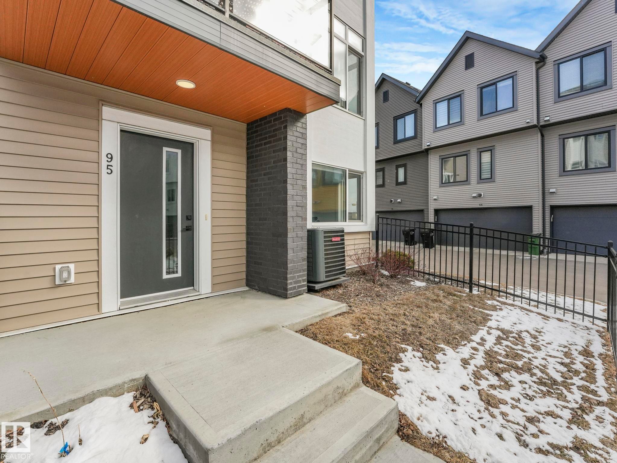 The property features a modern exterior with horizontal siding and a dark gray front door with a vertical glass insert - 95 1010 Rabbit Hill Road, Edmonton, AB - Outdoor