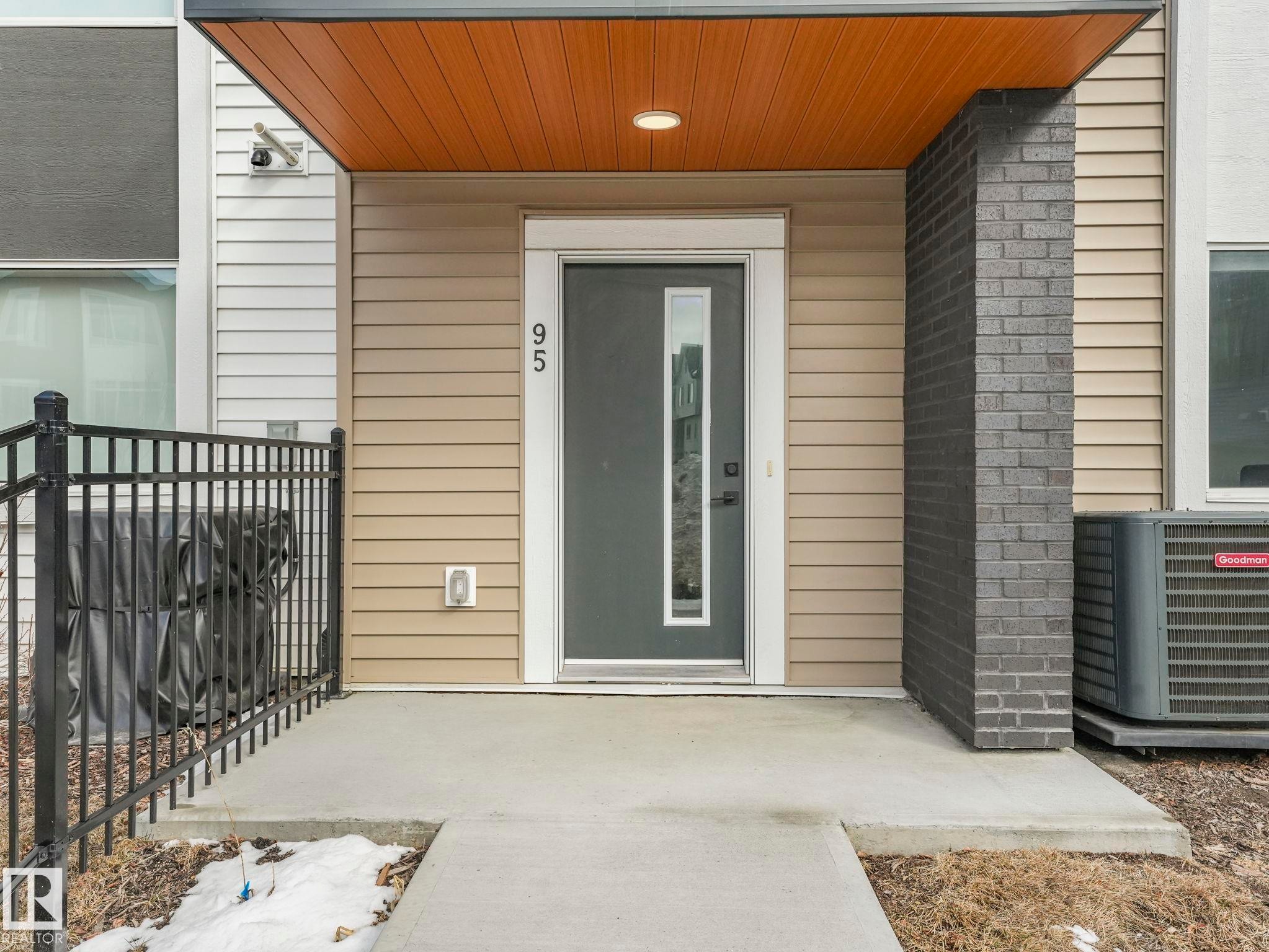 The property features a contemporary entryway with a dark grey door, vertical window accent, and distinctive house numbers - 95 1010 Rabbit Hill Road, Edmonton, AB - Outdoor With Exterior
