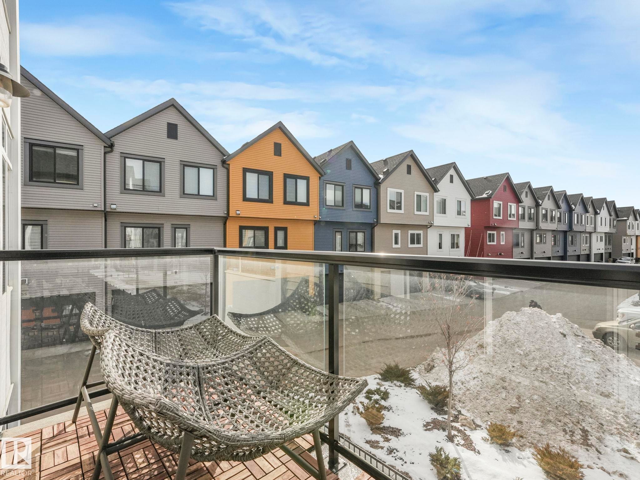 The property features a balcony with a glass railing and a wood-slat floor - 95 1010 Rabbit Hill Road, Edmonton, AB - Outdoor With Facade