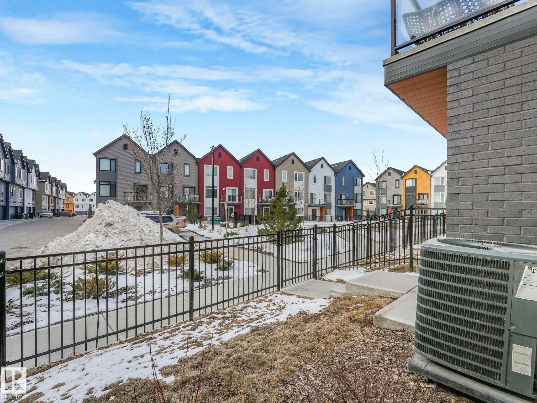 View of the neighborhood featuring a paved road, sidewalks, and a variety of colorful row houses - 95 1010 Rabbit Hill Road, Edmonton, AB - Outdoor