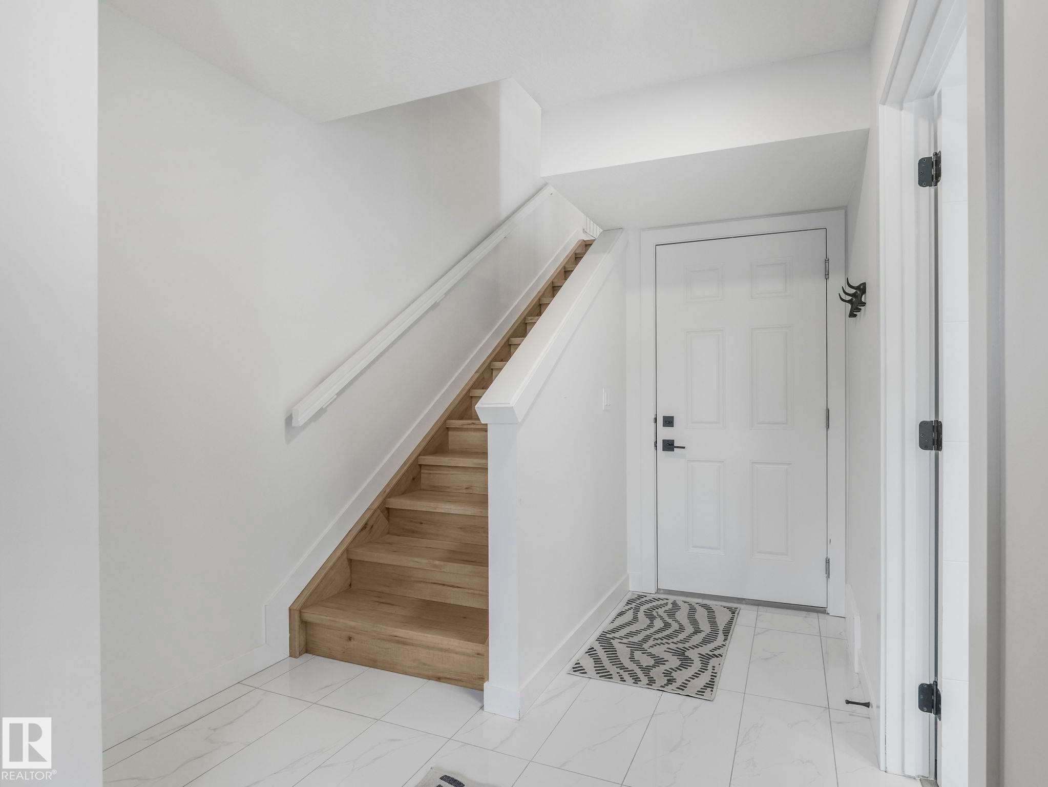 Entryway featuring light hardwood stairs with a white railing, a white front door, and tiled flooring - 95 1010 Rabbit Hill Road, Edmonton, AB - Indoor Photo Showing Other Room