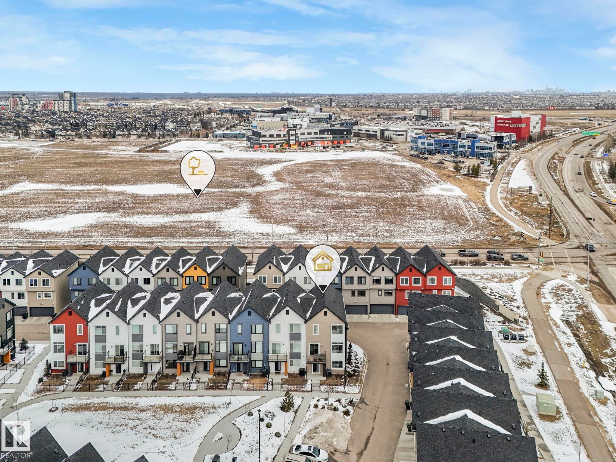 Aerial view of the property and surrounding neighborhood, featuring townhouses with distinct rooflines and a well-maintained road network - 95 1010 Rabbit Hill Road, Edmonton, AB - Outdoor With View