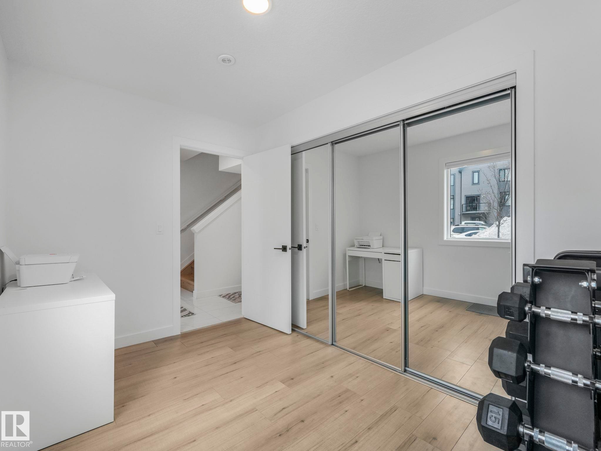 This versatile room features light-colored flooring, white walls, and a large window providing natural light - 95 1010 Rabbit Hill Road, Edmonton, AB - Indoor