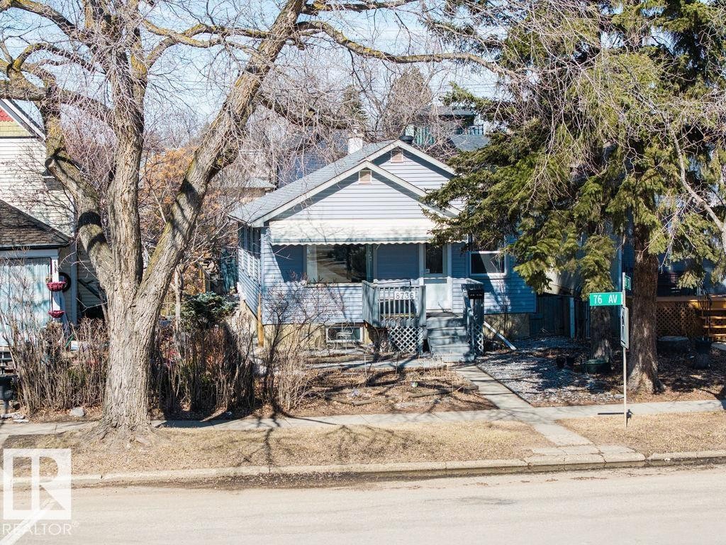 The property features a light blue exterior with white trim, a covered porch, and a sidewalk leading to the entrance - 8736 76 Avenue, Edmonton, AB - Outdoor