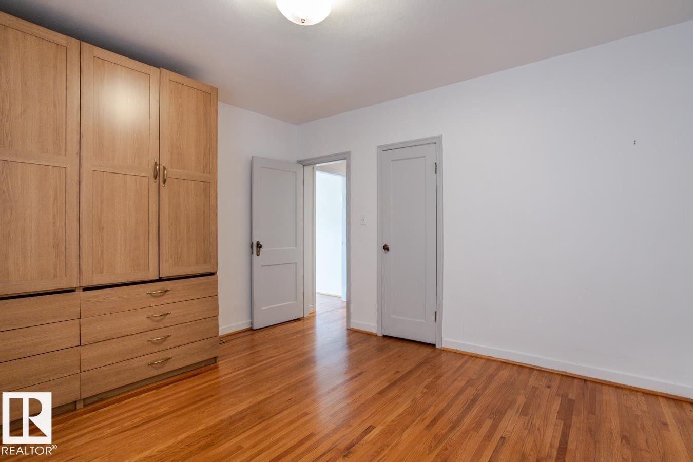 This room features hardwood floors and a white ceiling with a flush-mount light fixture - 8736 76 Avenue, Edmonton, AB - Indoor Photo Showing Other Room