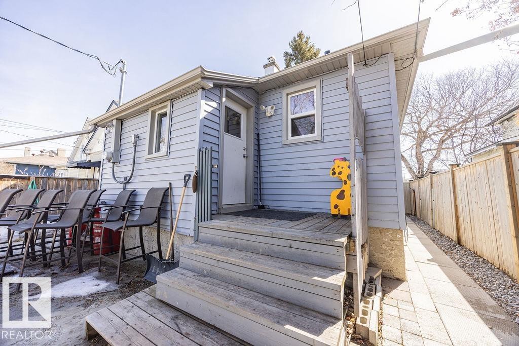 The property features light blue siding, a wooden deck with steps, and a white back door - 8736 76 Avenue, Edmonton, AB - Outdoor With Deck Patio Veranda